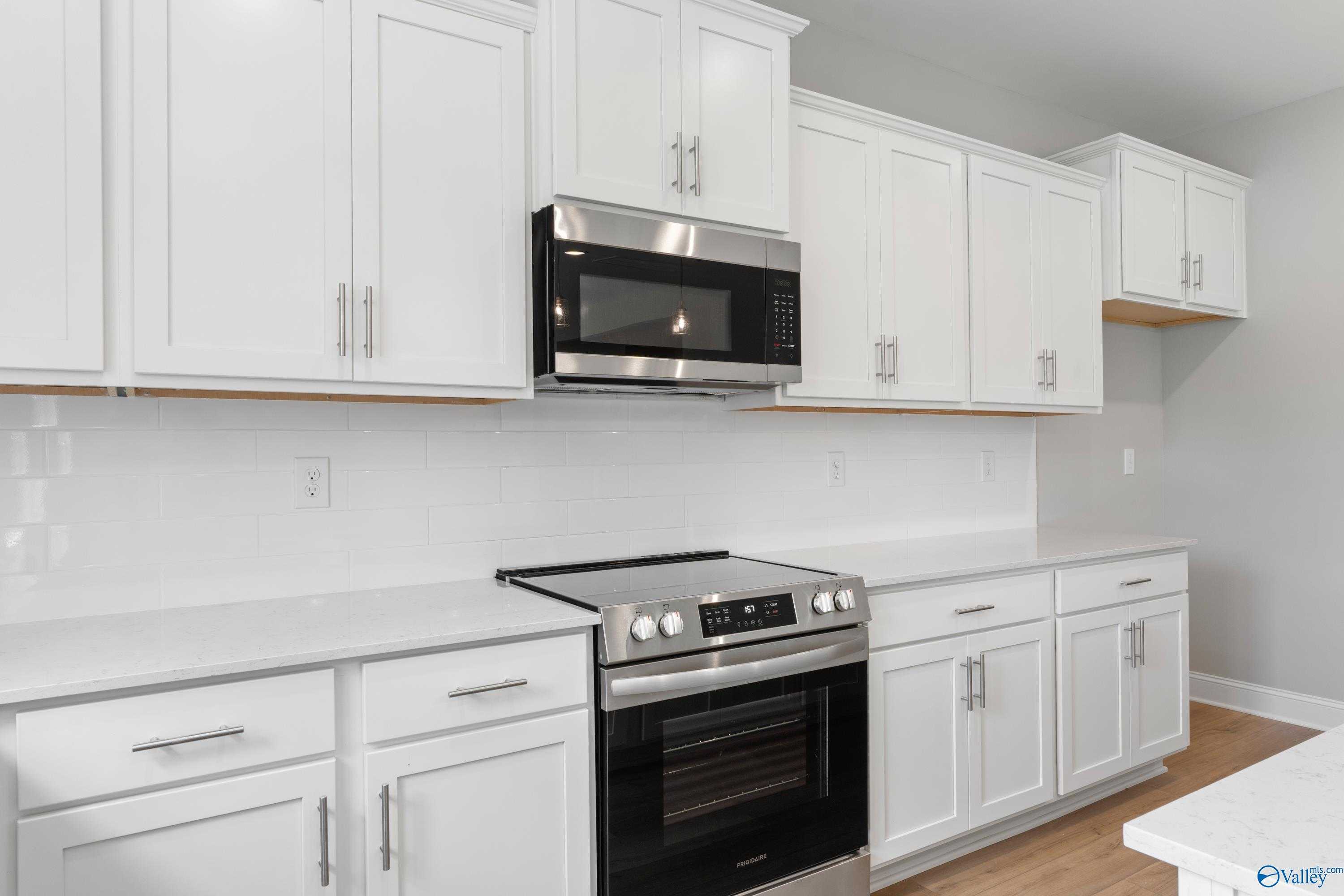 Modern kitchen featuring white shaker cabinets, stainless steel range and microwave, quartz counters in Davidson Homes The Chelsea B, New Market, AL