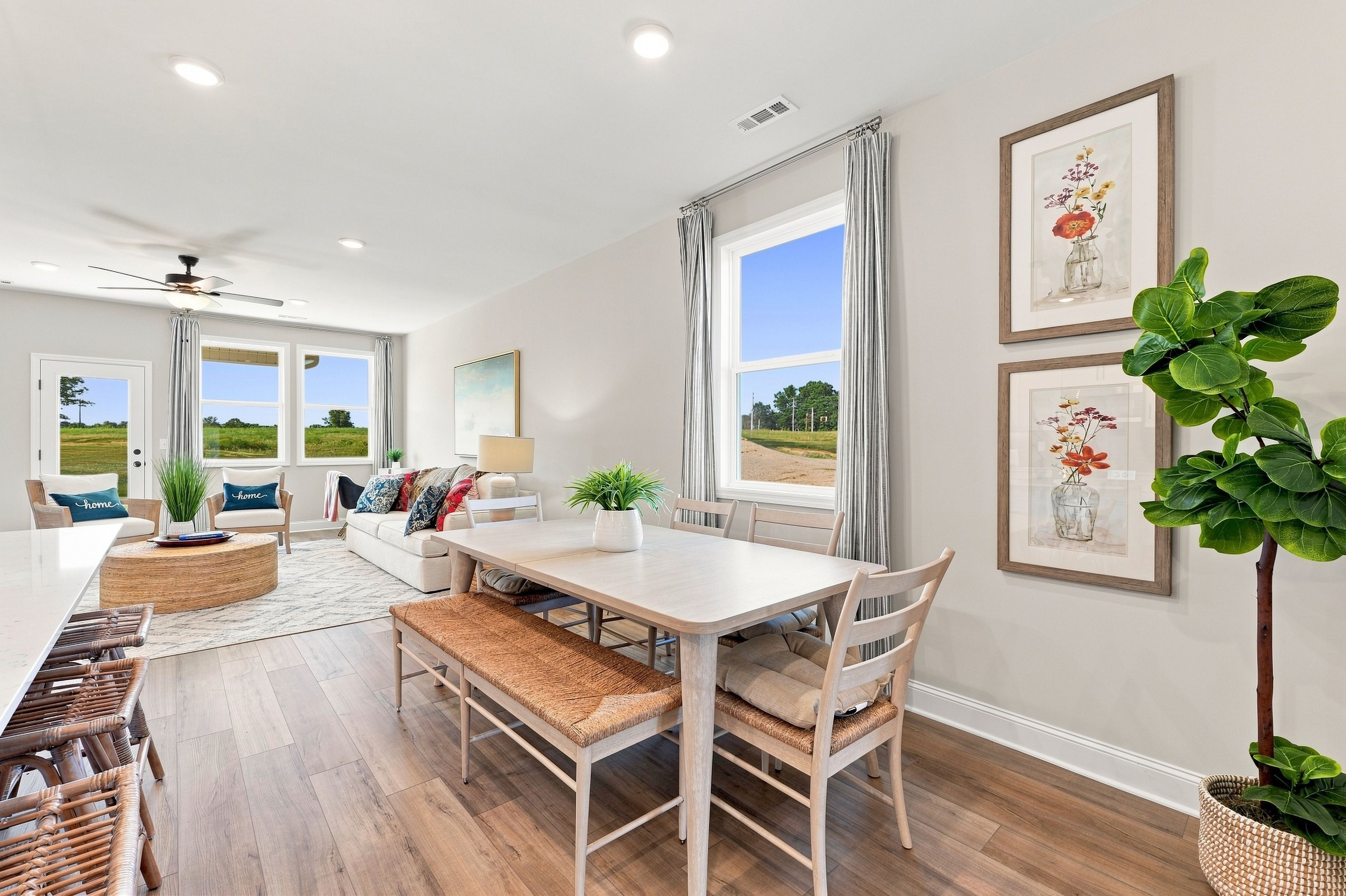Bright open-concept dining and living area at Bailey Park in Fayetteville, TN by Davidson Homes with hardwood floors and large windows