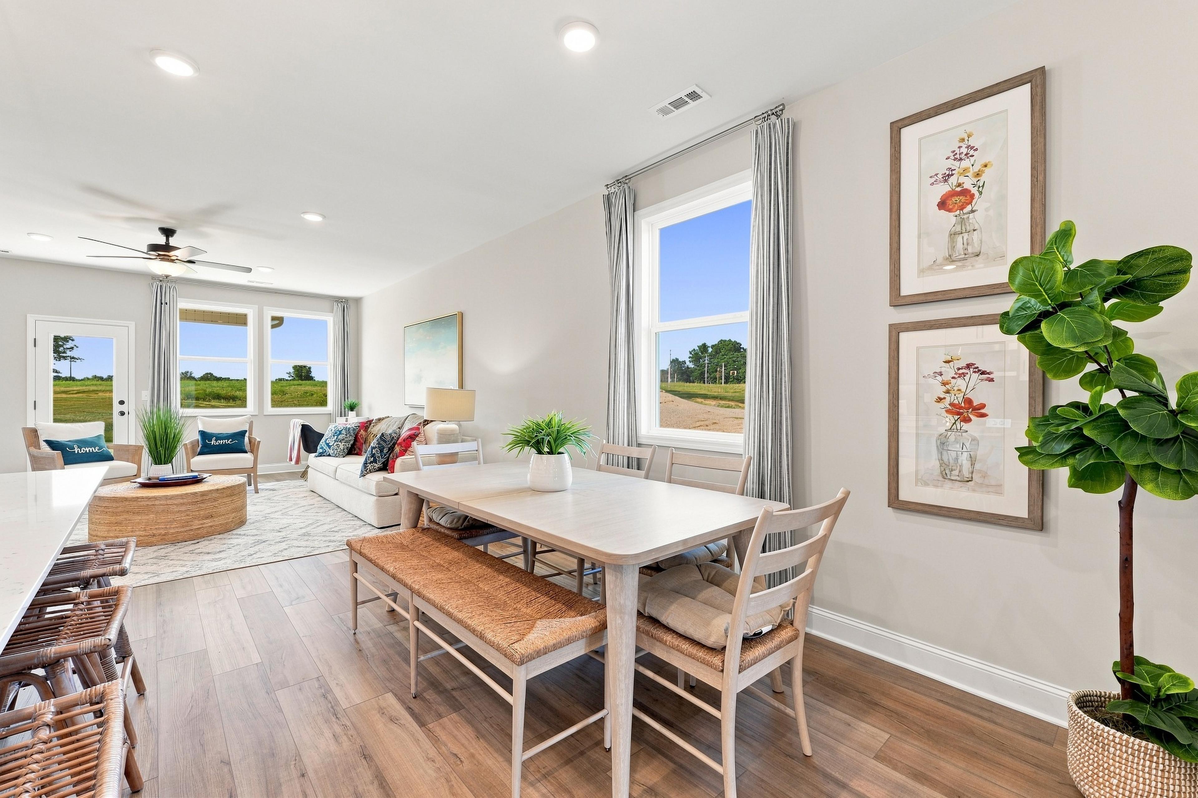 Bright open-concept dining and living area at Bailey Park in Fayetteville, TN by Davidson Homes with hardwood floors and large windows