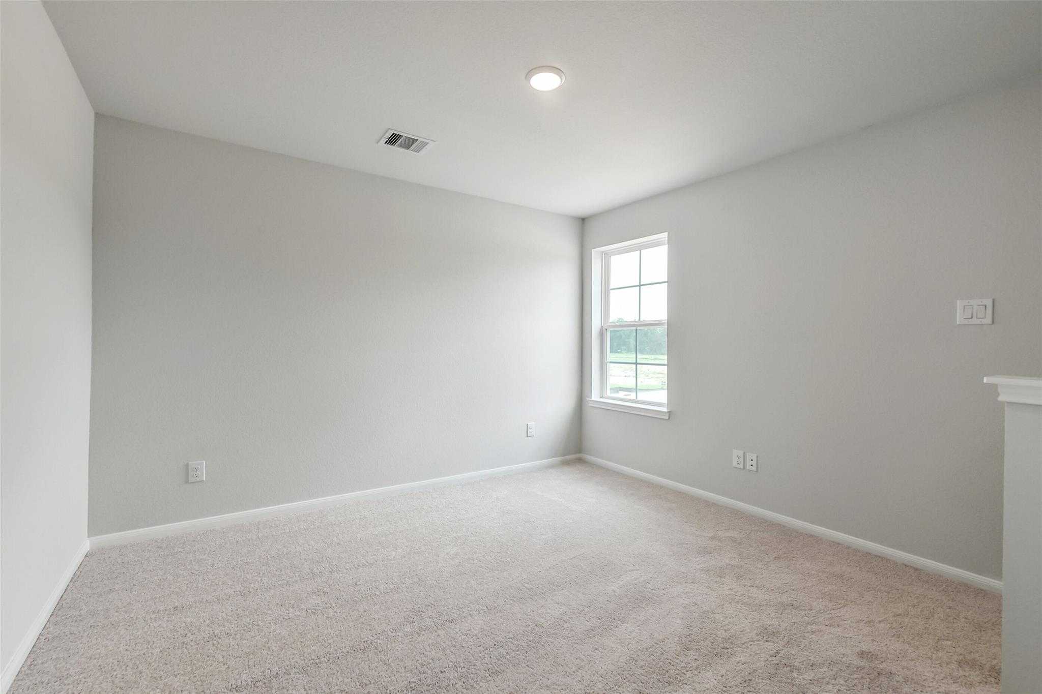Spacious empty bedroom with gray walls, beige carpet, large window in Davidson Homes The Sabine E, Conroe, Texas