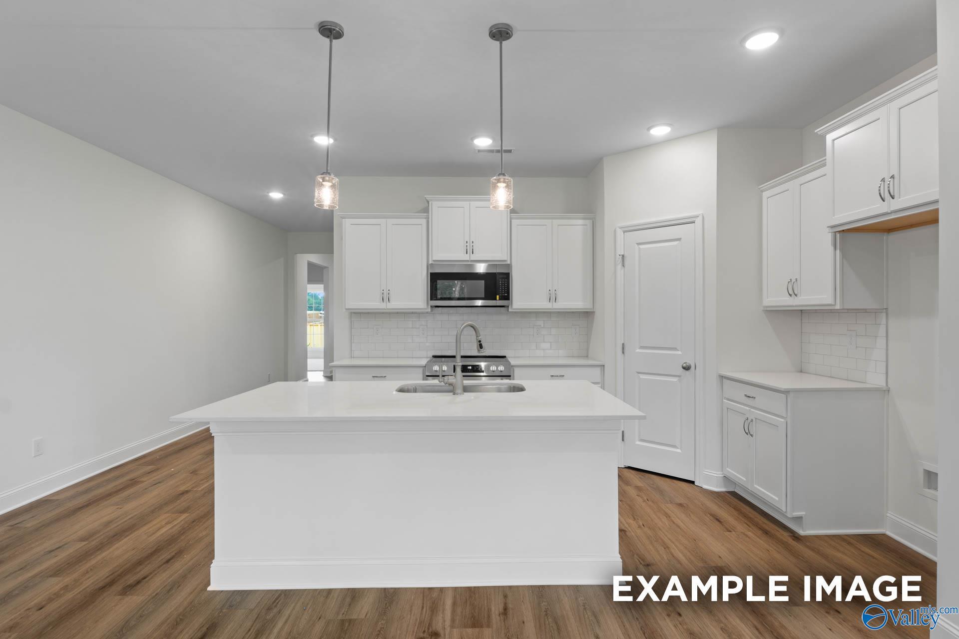 Modern white kitchen island with stainless appliances and subway tile backsplash in 4-bedroom Daphne E home, Evermore Homes, Harvest AL