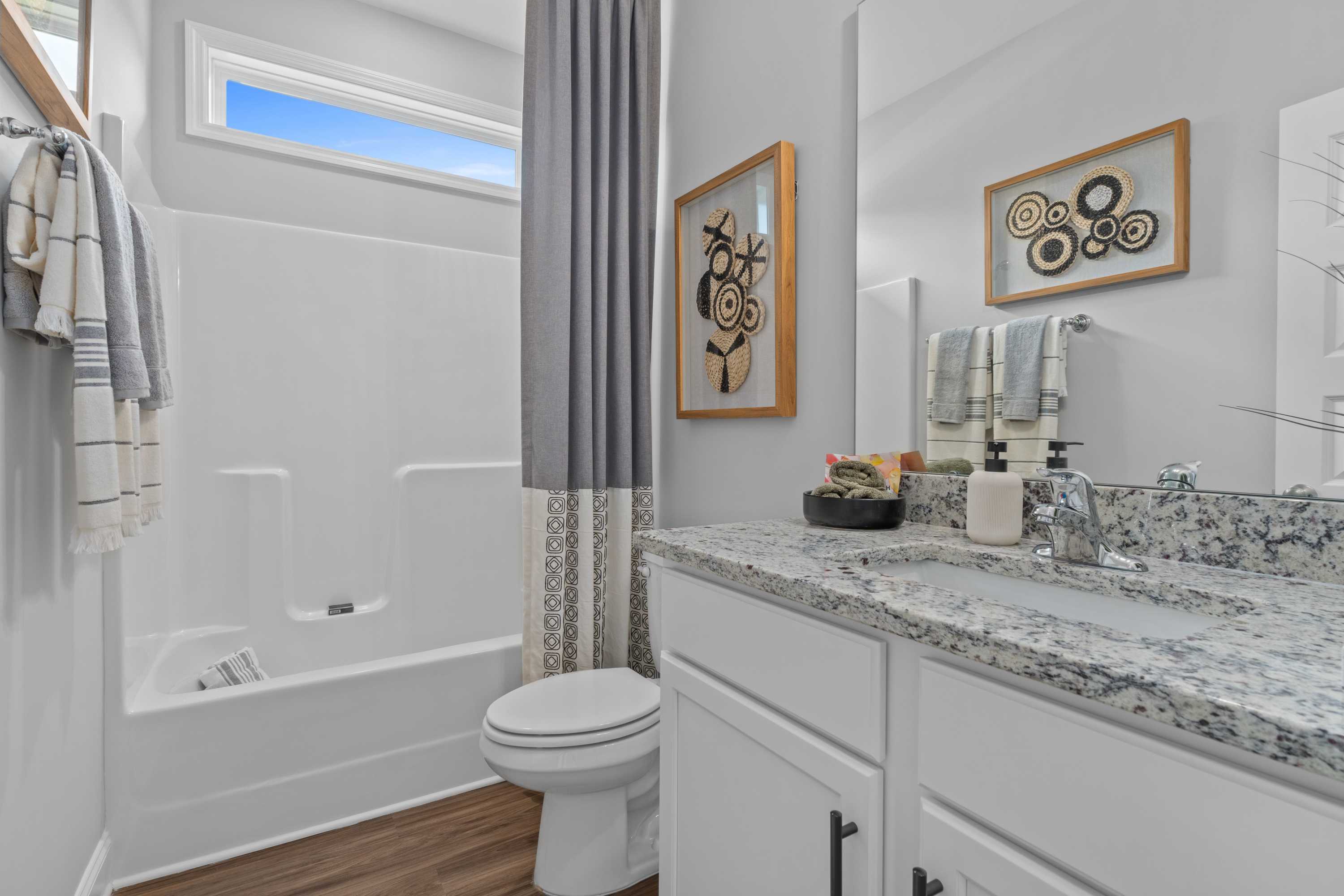 Spacious bathroom at Wood Trail in Toney Alabama with tub shower combo, marble vanity, and hardwood floors