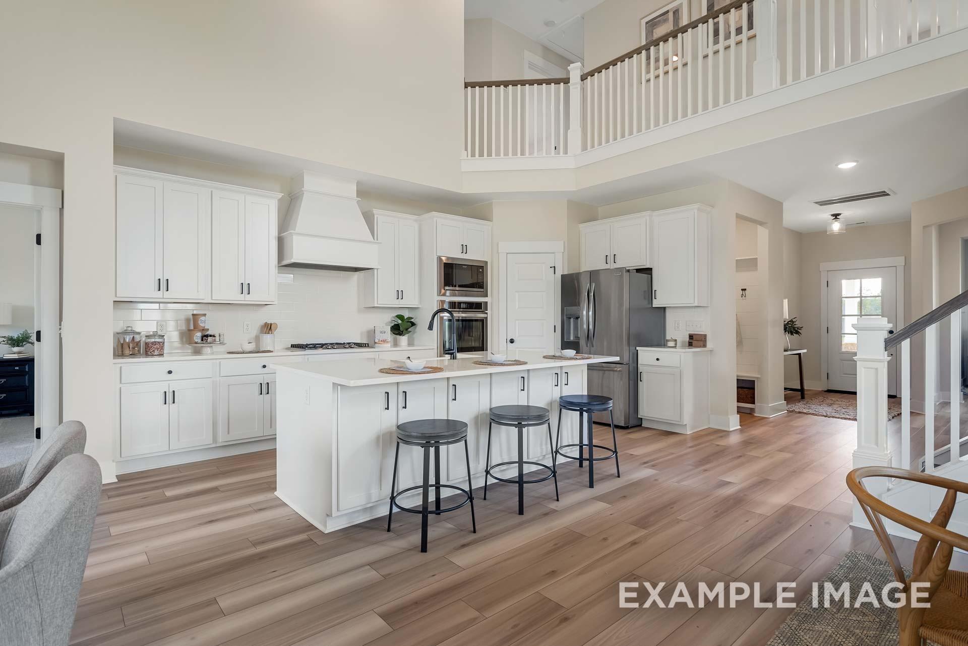 Modern open-concept kitchen with white shaker cabinets, large center island, stainless appliances, and two-story great room in Davidson Homes The Ridgeport, Gallatin, TN