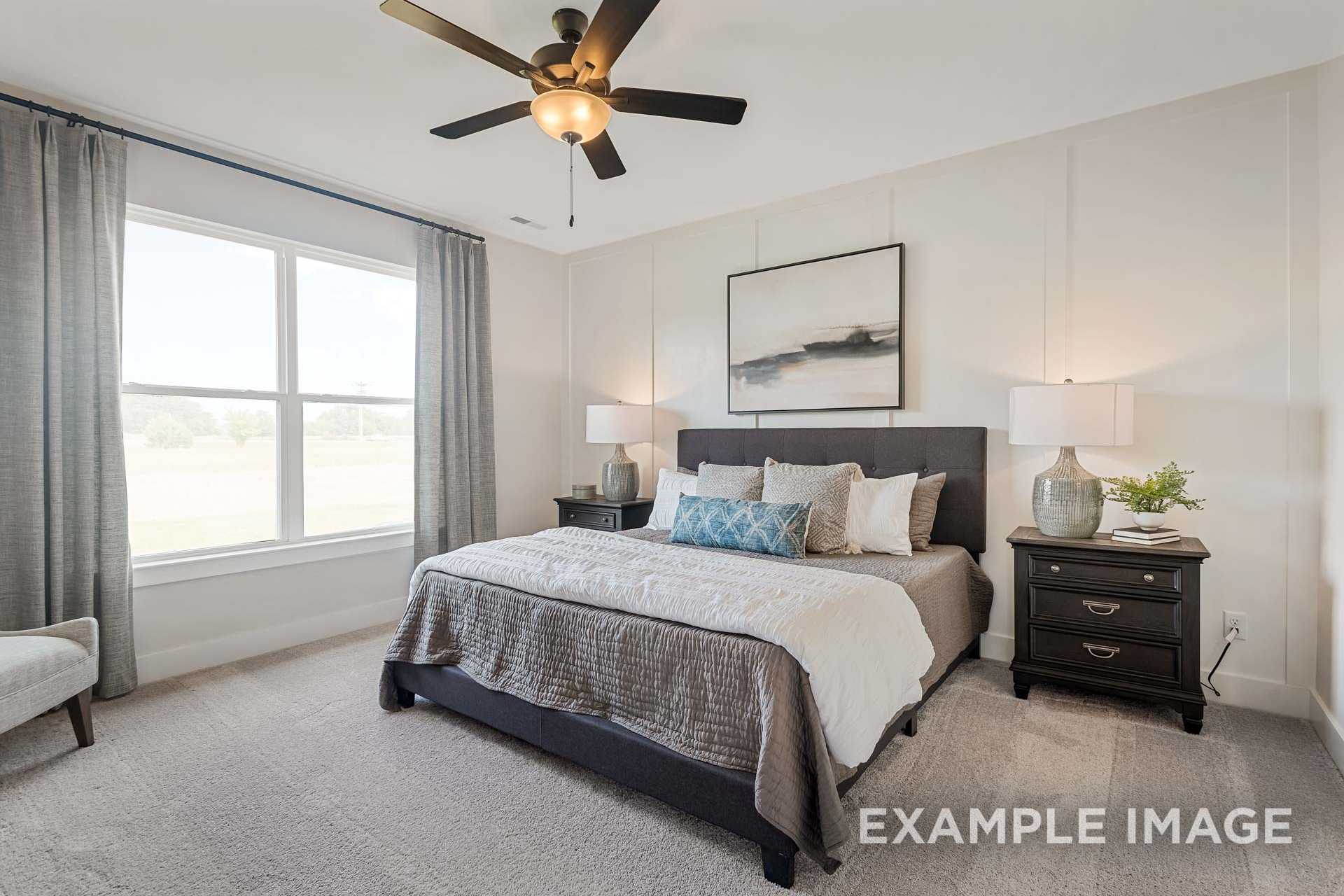 Spacious master bedroom in The Ridgeport B featuring king bed with gray bedding, ceiling fan, and large curtained windows