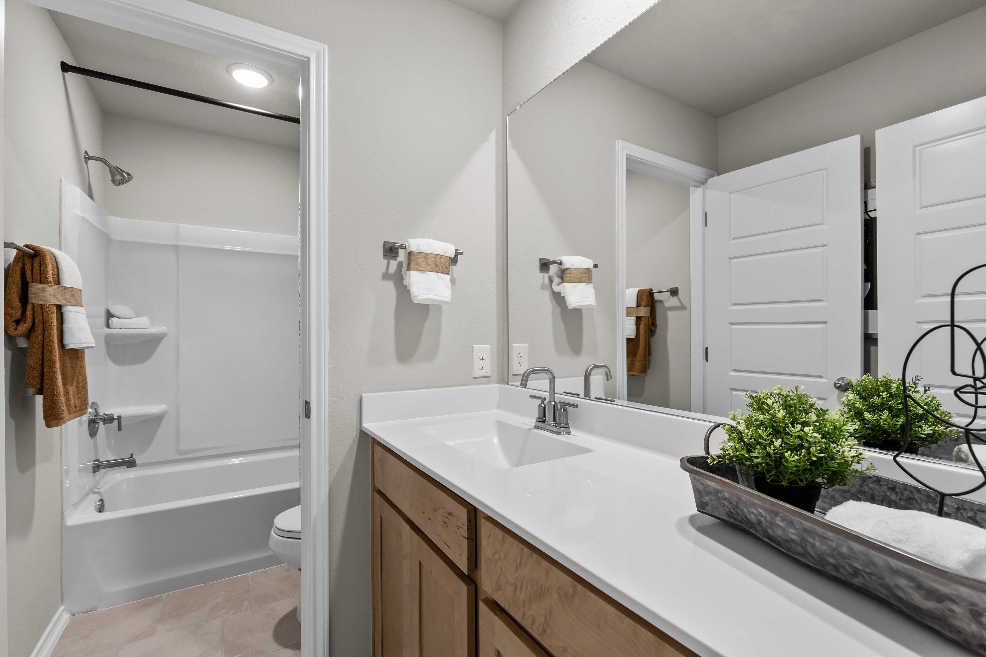 Modern primary bathroom at Applewhite Meadows in San Antonio TX with double vanity, bathtub, and glass shower