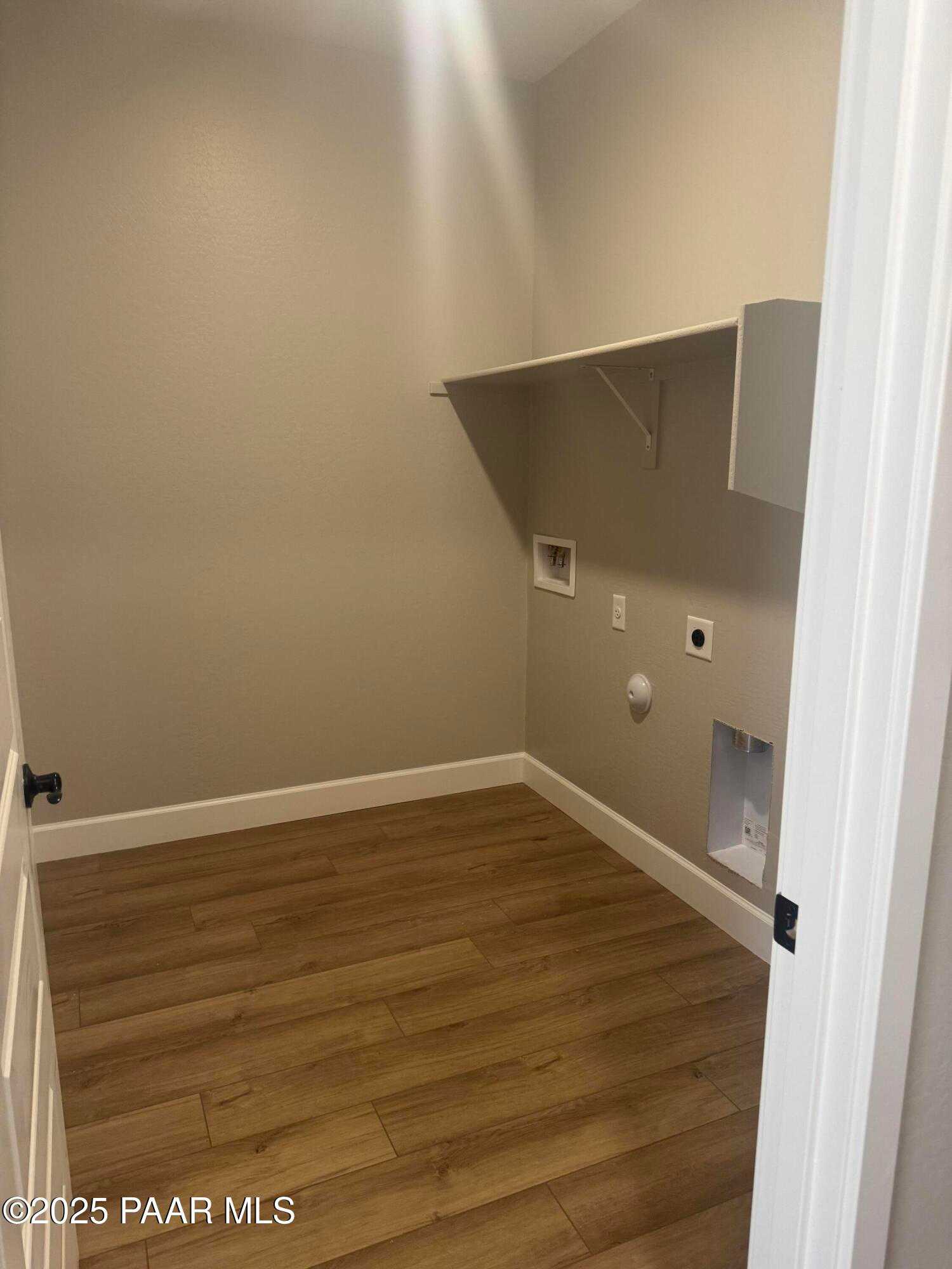 Bright laundry room with white cabinets, washer-dryer hookups, and laminate wood floors in Evermore Homes The Summit B, Prescott Valley