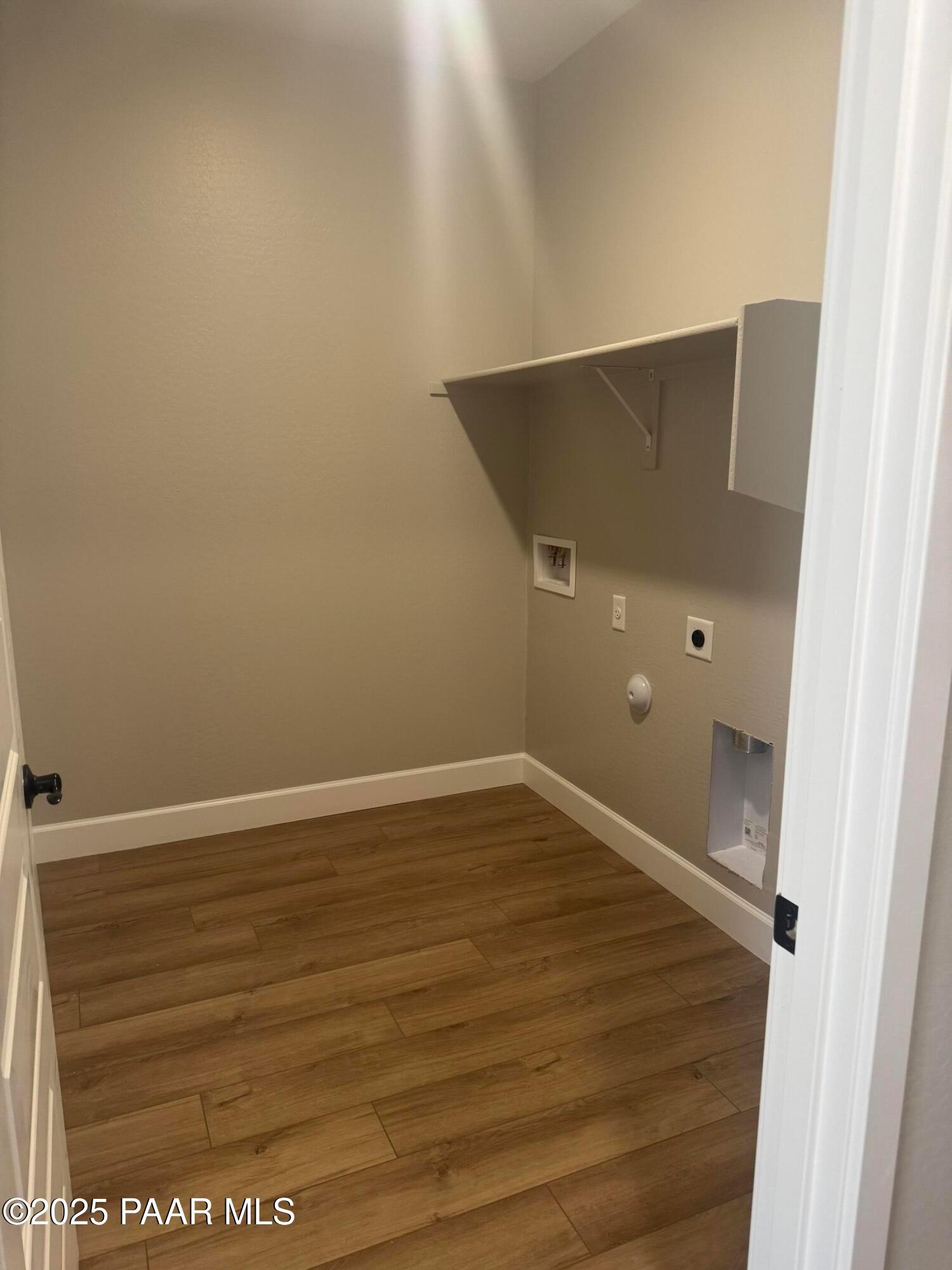 Bright laundry room with white cabinets, washer-dryer hookups, and laminate wood floors in Evermore Homes The Summit B, Prescott Valley