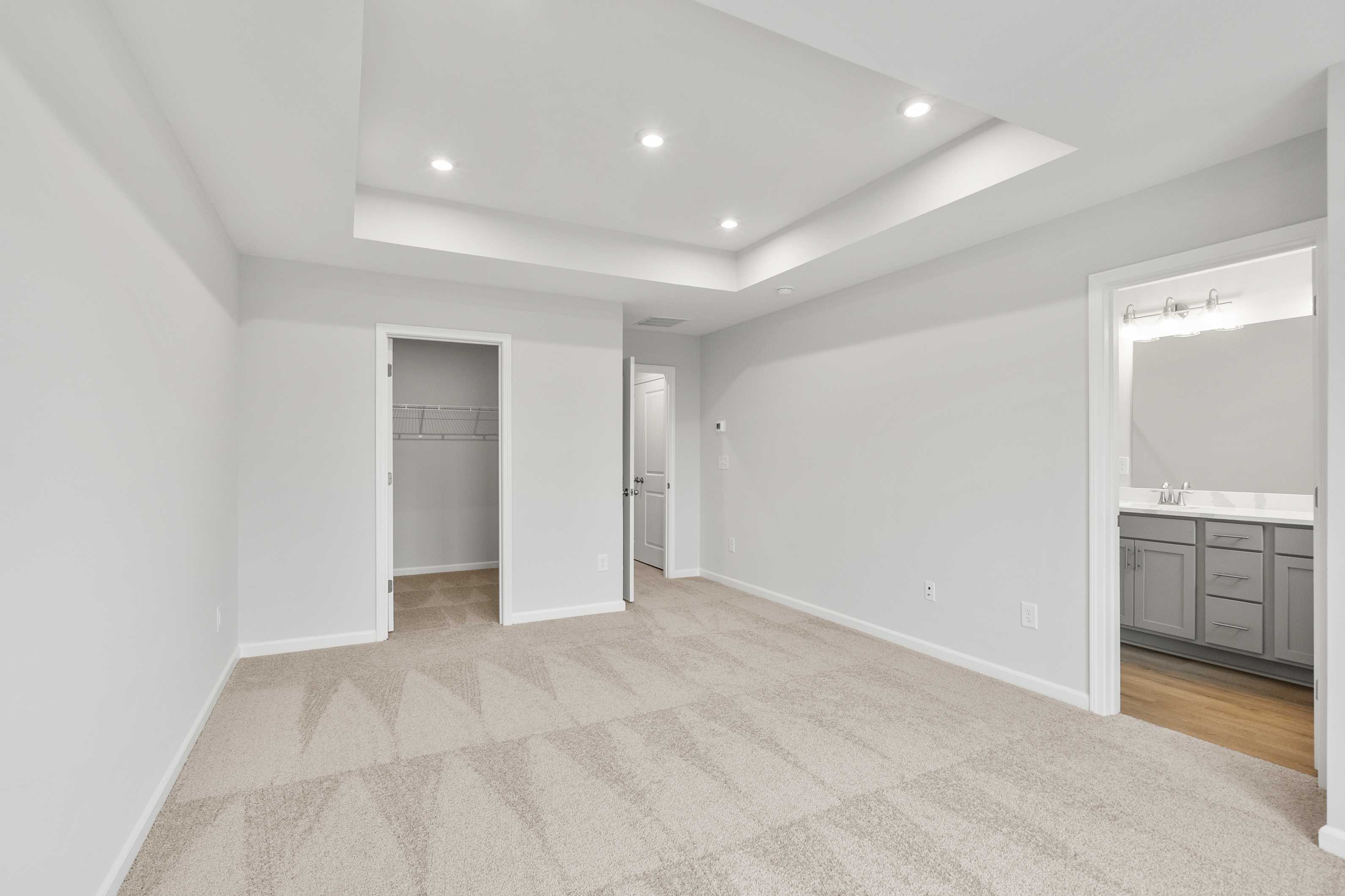 Spacious master suite in The Durant A featuring tray ceiling, walk-in closet, and en-suite bath with double vanity