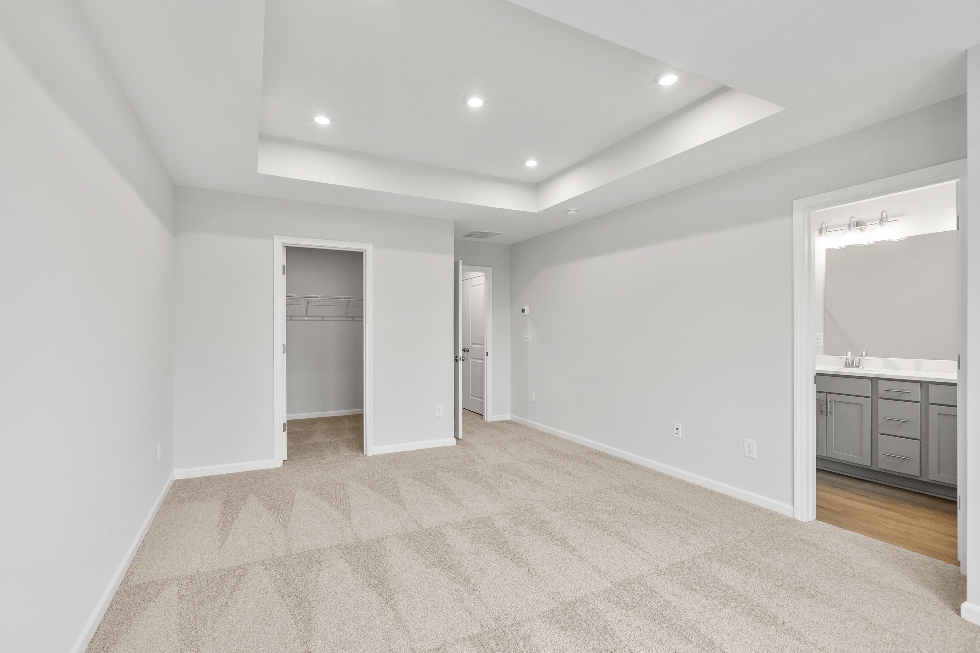 Spacious master suite in The Durant A featuring tray ceiling, walk-in closet, and en-suite bath with double vanity