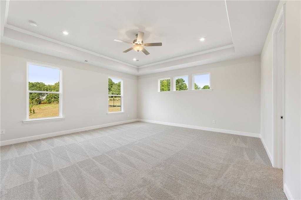 Bright upstairs bedroom with large windows overlooking trees and fields, ceiling fan, and gray carpet in Davidson Homes The Hampton C, Buford, GA