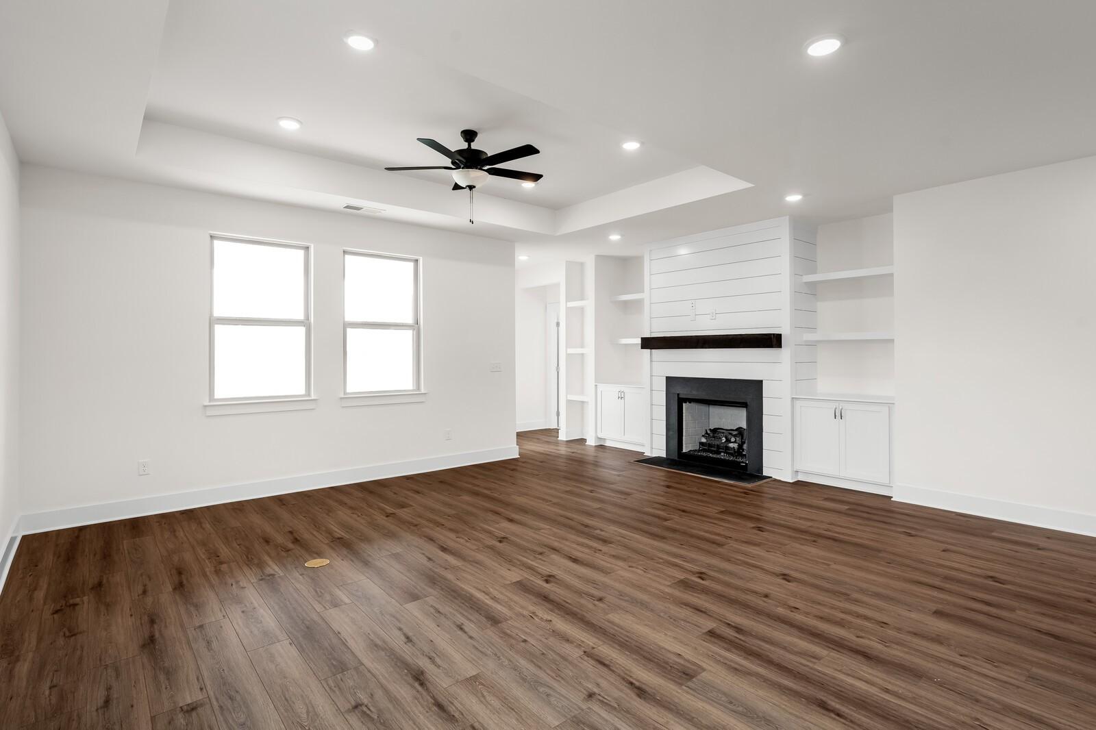 Open-concept living room with shiplap fireplace and tray ceiling in The Prairie C floor plan at Woods Crossing, Gallatin.