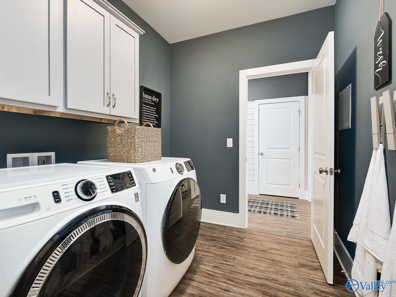 Functional laundry room with white GE washer dryer, custom cabinets, gray walls in Davidson Homes The Everett, Toney AL