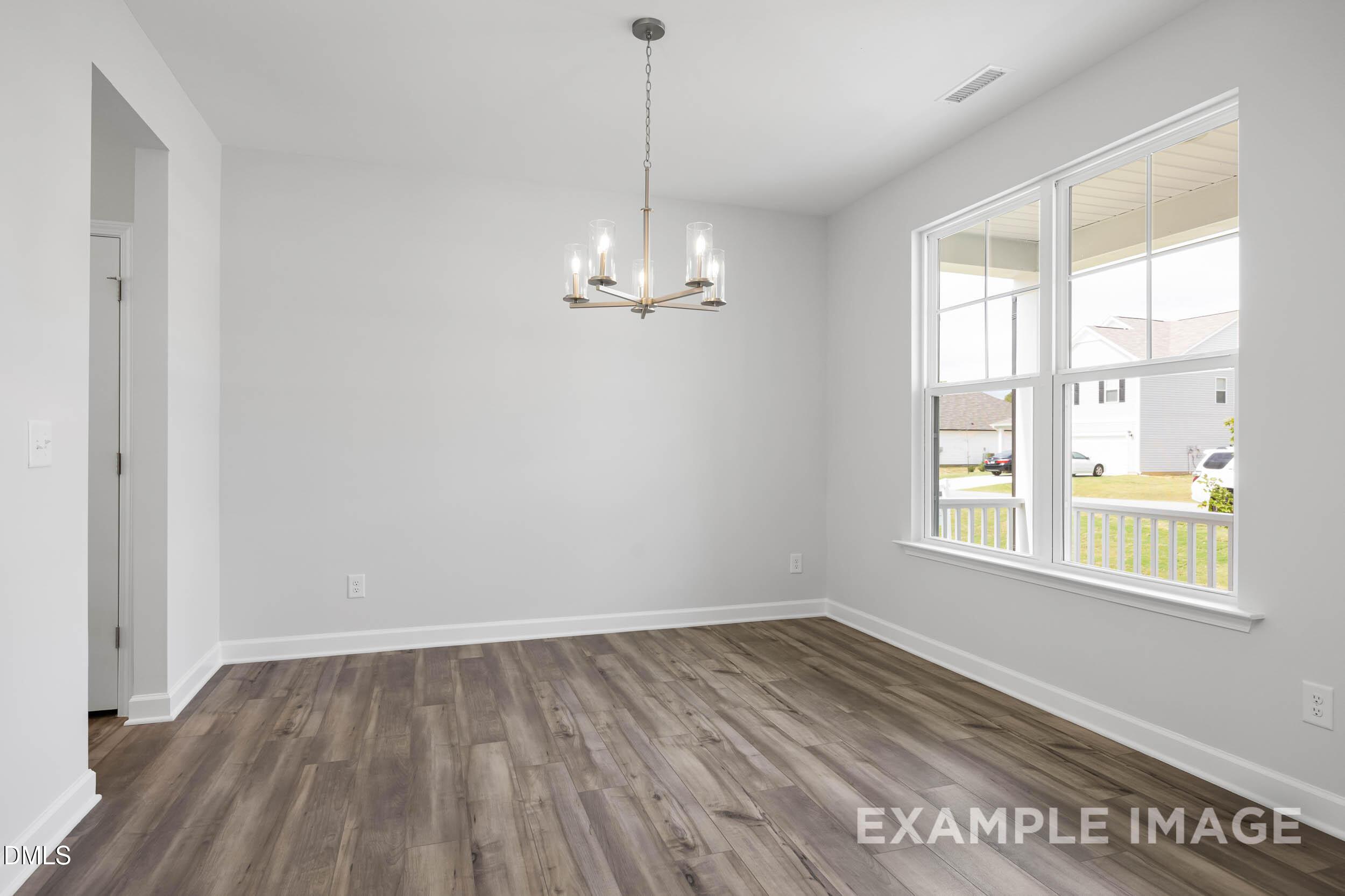 Elegant dining room with chandelier, large windows to porch, hardwood floors in Davidson Homes The Ash B, Lillington, NC