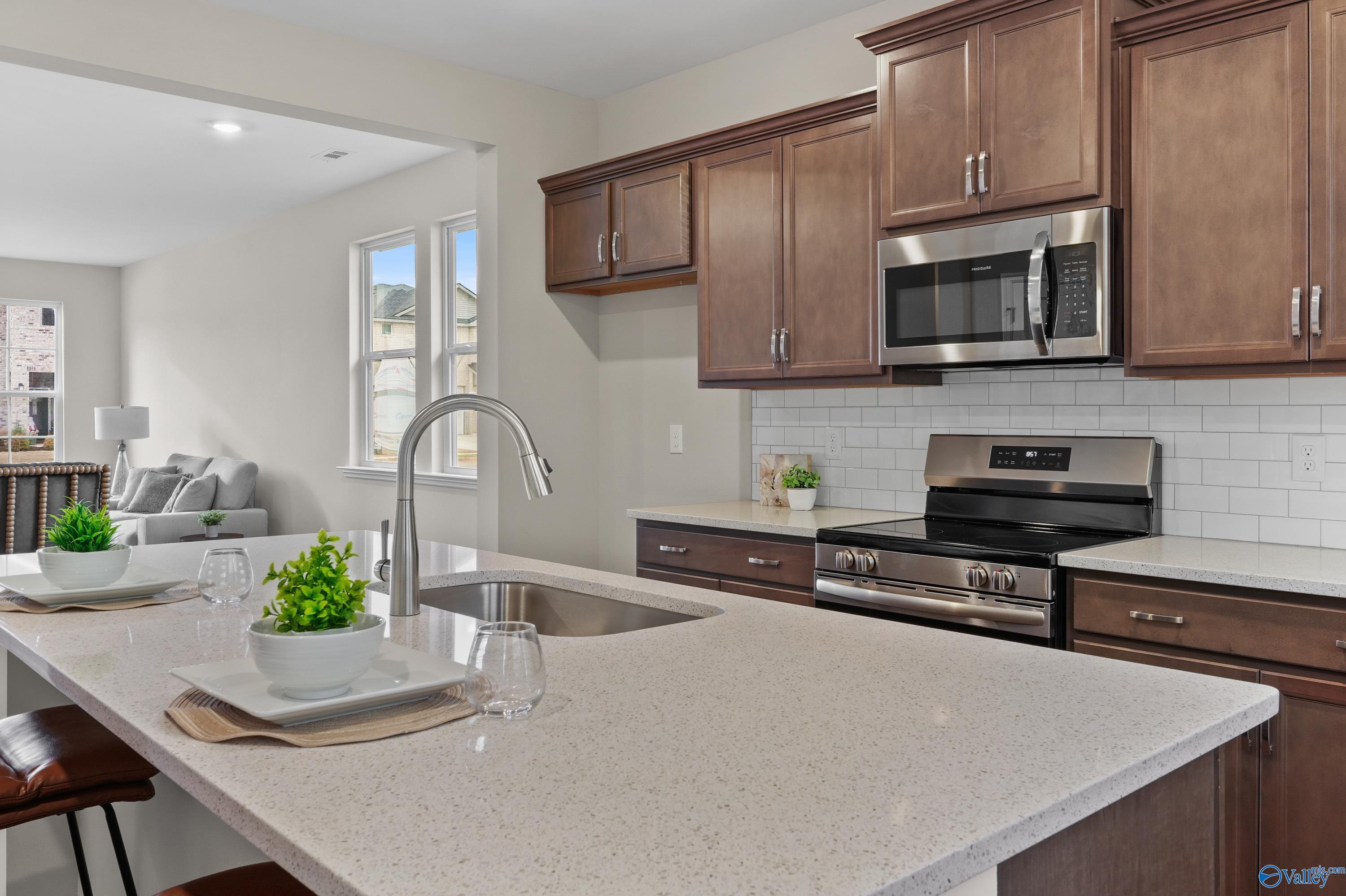 Spacious open-concept kitchen with quartz counters, stainless appliances, and island in Davidson Homes The Stella, Hazel Green AL