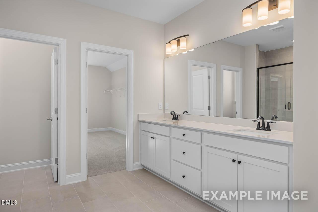 Elegant master bathroom with white double vanity, quartz counters, mirrors, and glass shower in Davidson Homes Crawford D, Angier, NC