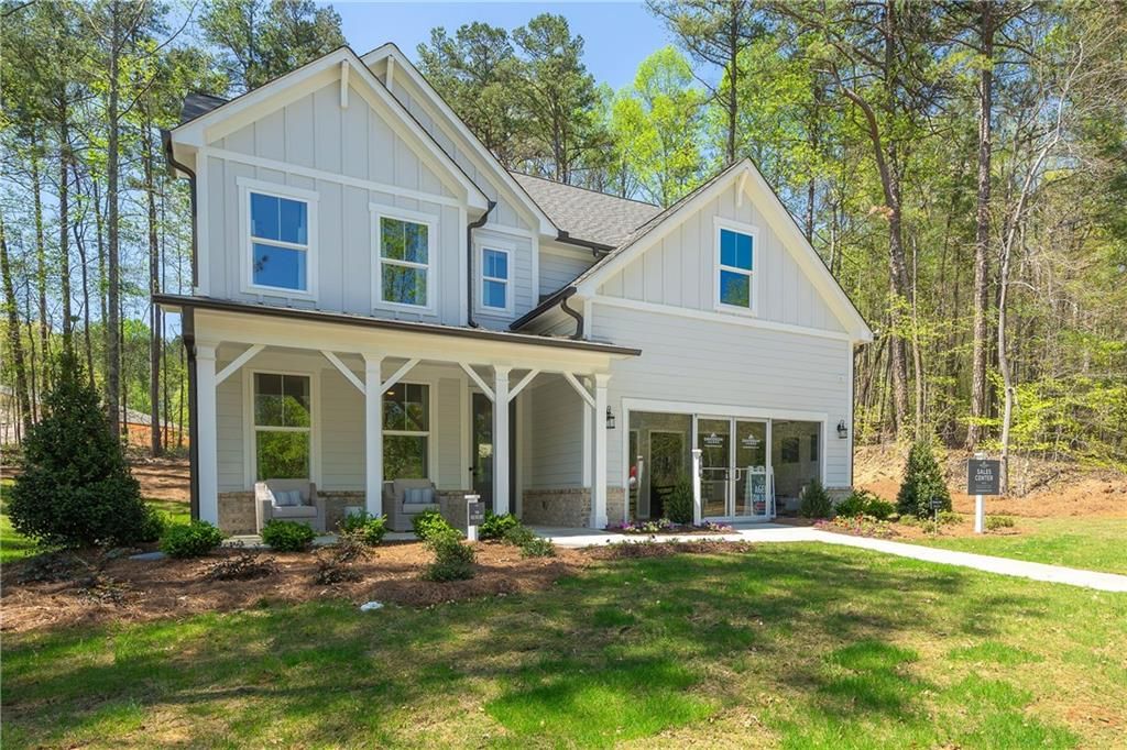 Charming two-story 5-bedroom home exterior with wraparound porch, white siding, and lush landscaping in Riverwood, Dallas, Georgia - Davidson Homes Willow B
