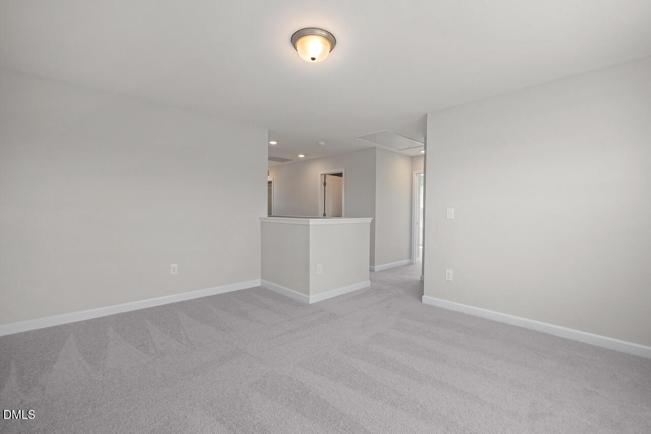 Spacious carpeted upper-level loft in The Grace C floor plan by Davidson Homes at Retreat at North Main, Lillington, NC.