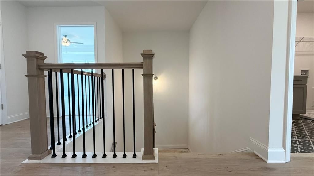 Modern staircase with wood railing and black iron balusters in a Davidson Homes floor plan at Wehunt Meadows, Hoschton, GA.