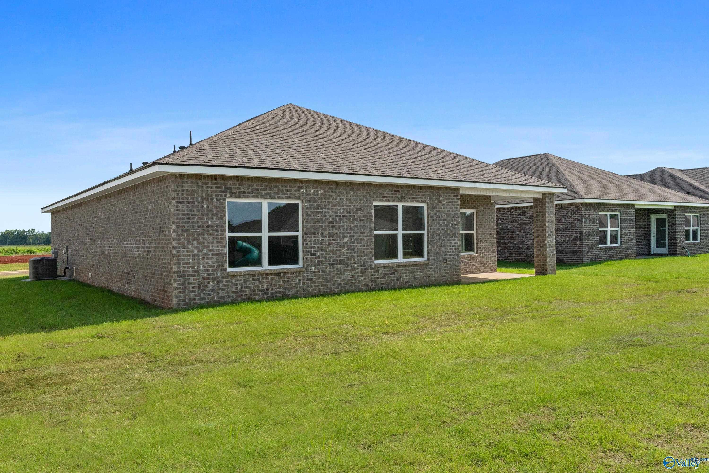 Single-story brick home exterior with 2-car garage, large windows, and covered patio in Clearview, Hazel Green, Alabama by Davidson Homes