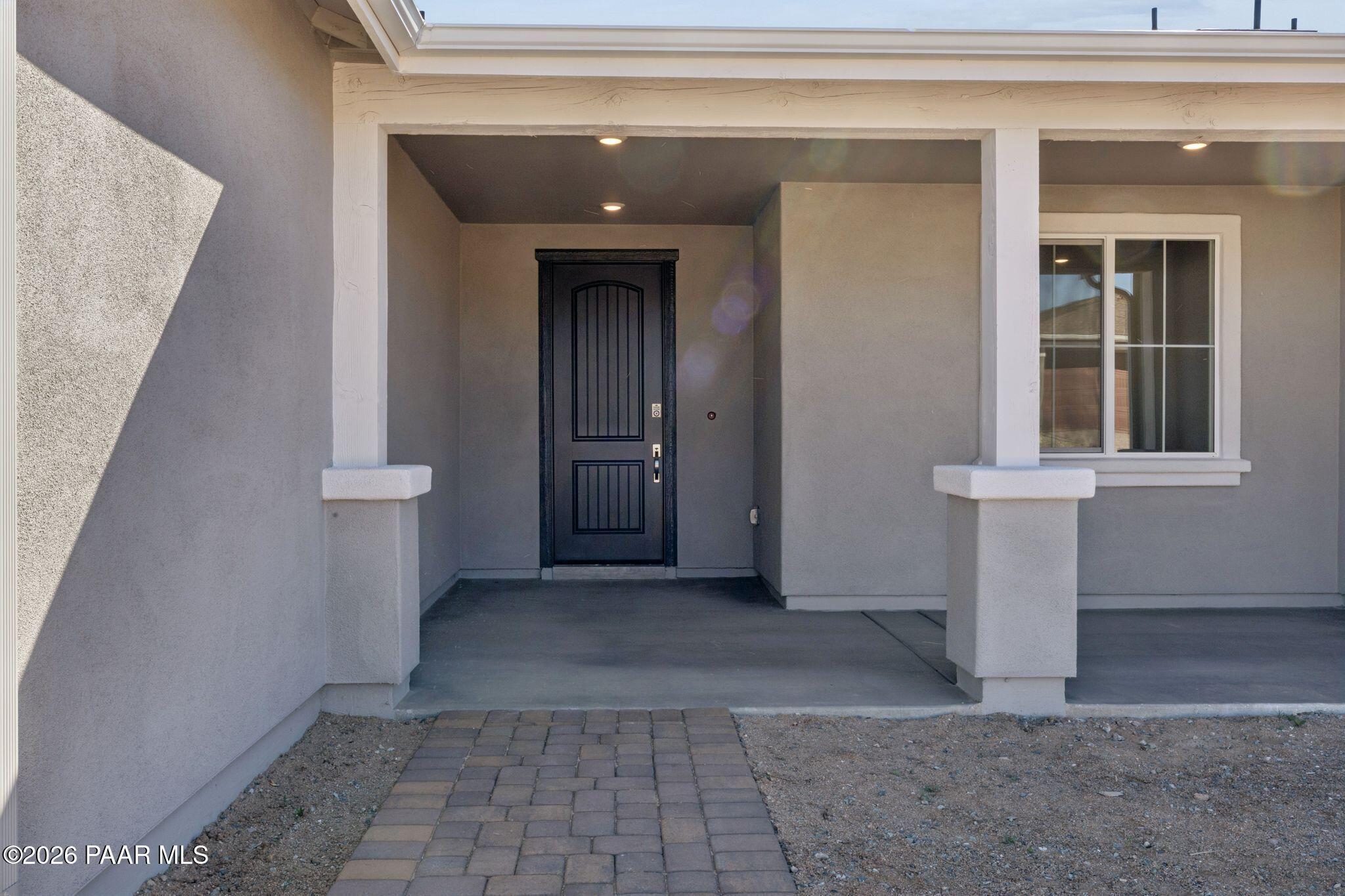 Elegant covered front porch with dark panelled door and beige stucco exterior in Davidson Homes The Monarch A, Prescott, Arizona
