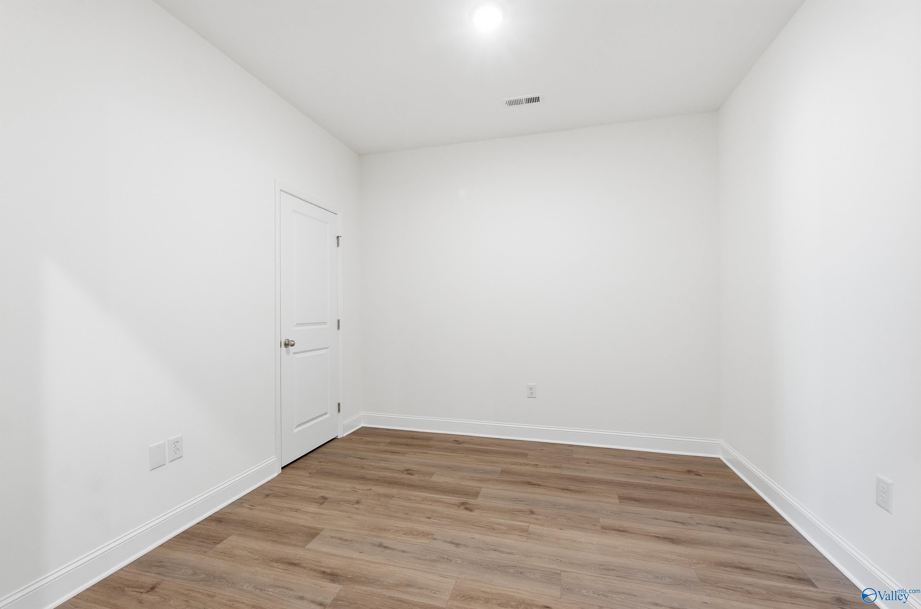 Spacious empty bedroom with white walls, light wood flooring, and ceiling vent in Davidson Homes The Cumberland D, Decatur, Alabama