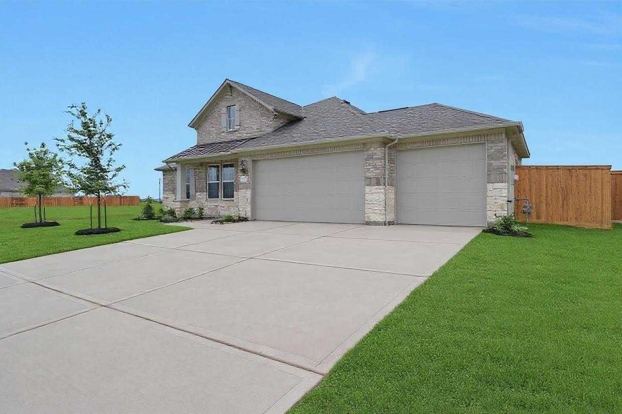 Single-story 3-bedroom home with 3-car garage, stone facade, concrete driveway, and lush front yard in Lago Mar, Texas City, Texas