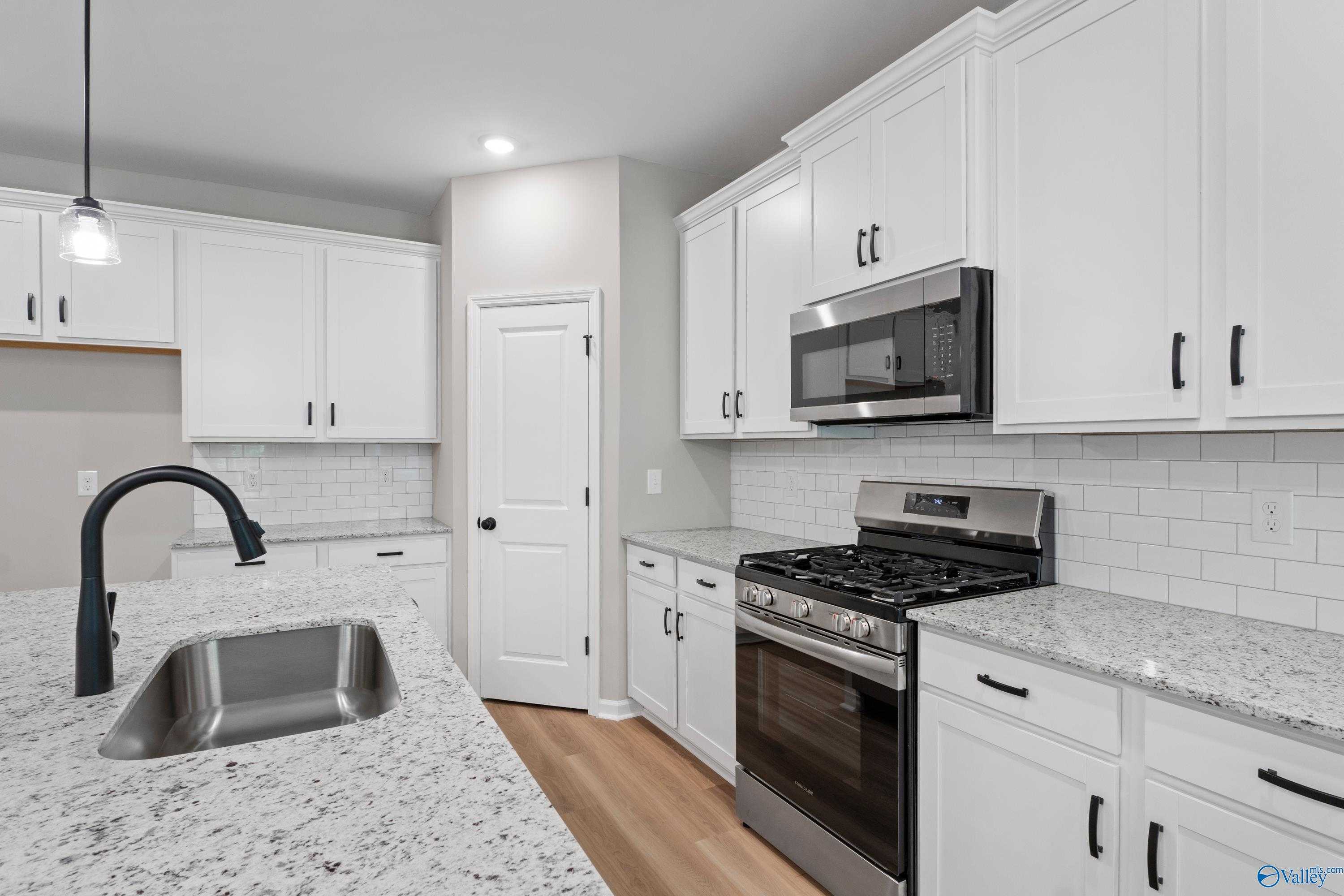 Contemporary kitchen with white cabinets, granite countertops, stainless steel appliances in Davidson Homes The Phoenix, Hazel Green, AL