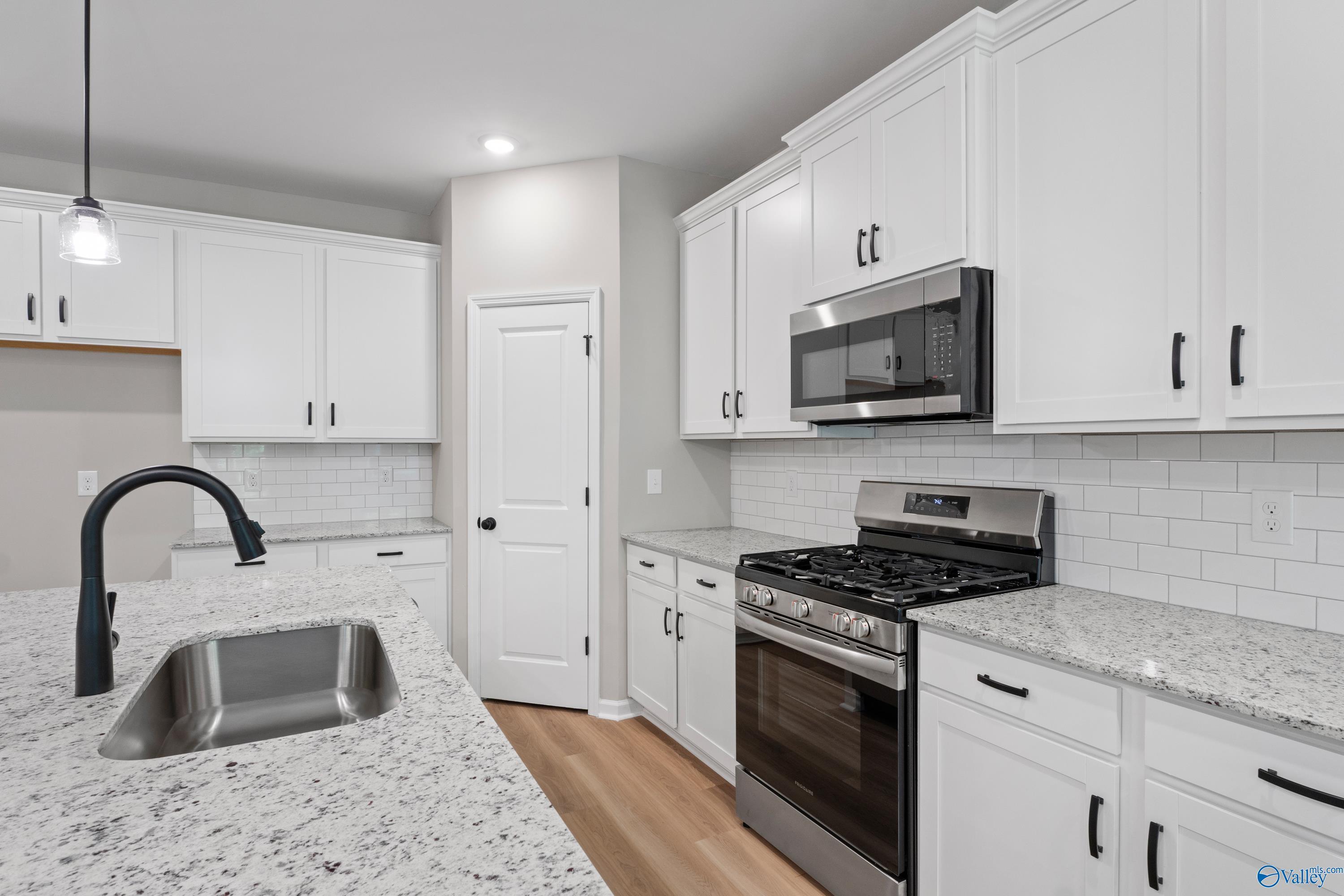 Modern white kitchen with granite counters, stainless appliances, subway tile backsplash in Davidson Homes The Phoenix, Hazel Green AL