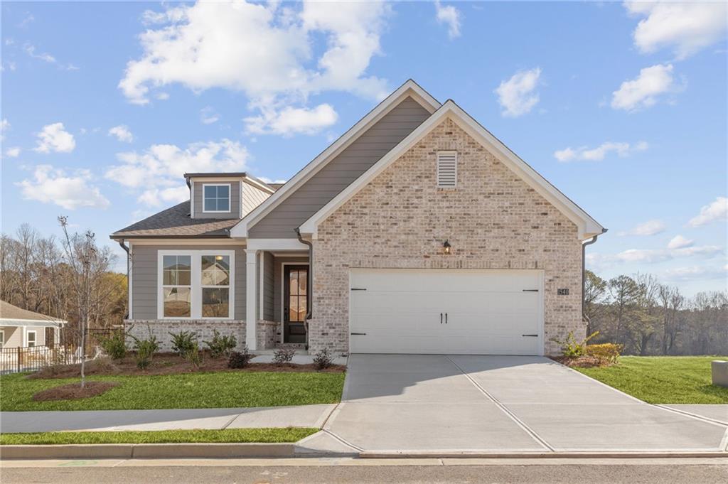 Modern beige brick single-story home with two-car garage, front porch, and landscaped yard in Kelly Preserve, Loganville, Georgia