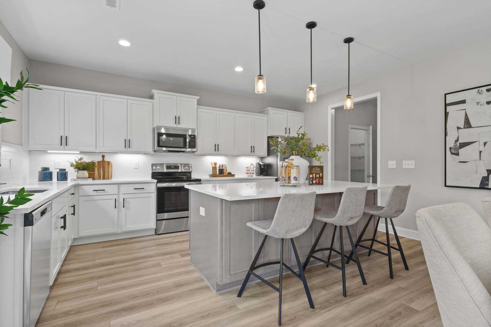 Contemporary kitchen in Creek Grove, New Market Alabama with white shaker cabinets, gray island bar stools, stainless appliances, and hardwood floors