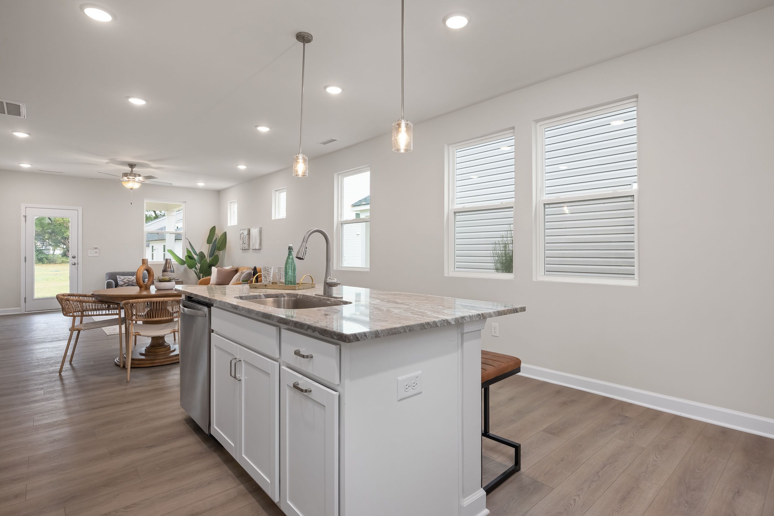 Open-concept kitchen and dining area at Gregory Village in Lillington, NC, featuring a stone island and wood flooring.