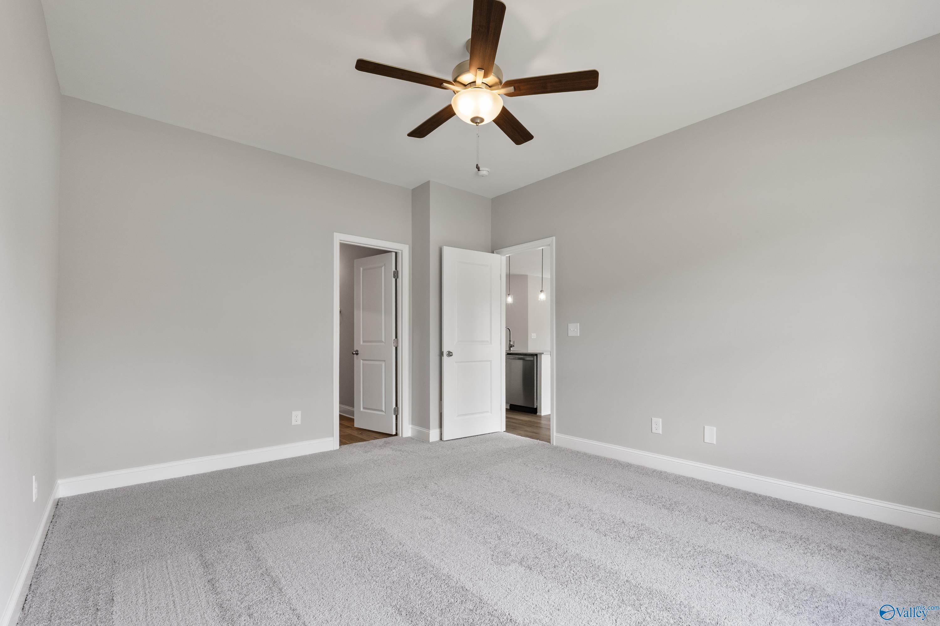 Spacious master bedroom with ceiling fan, gray carpet, and en-suite bath in Davidson Homes The Franklin C, Huntsville AL