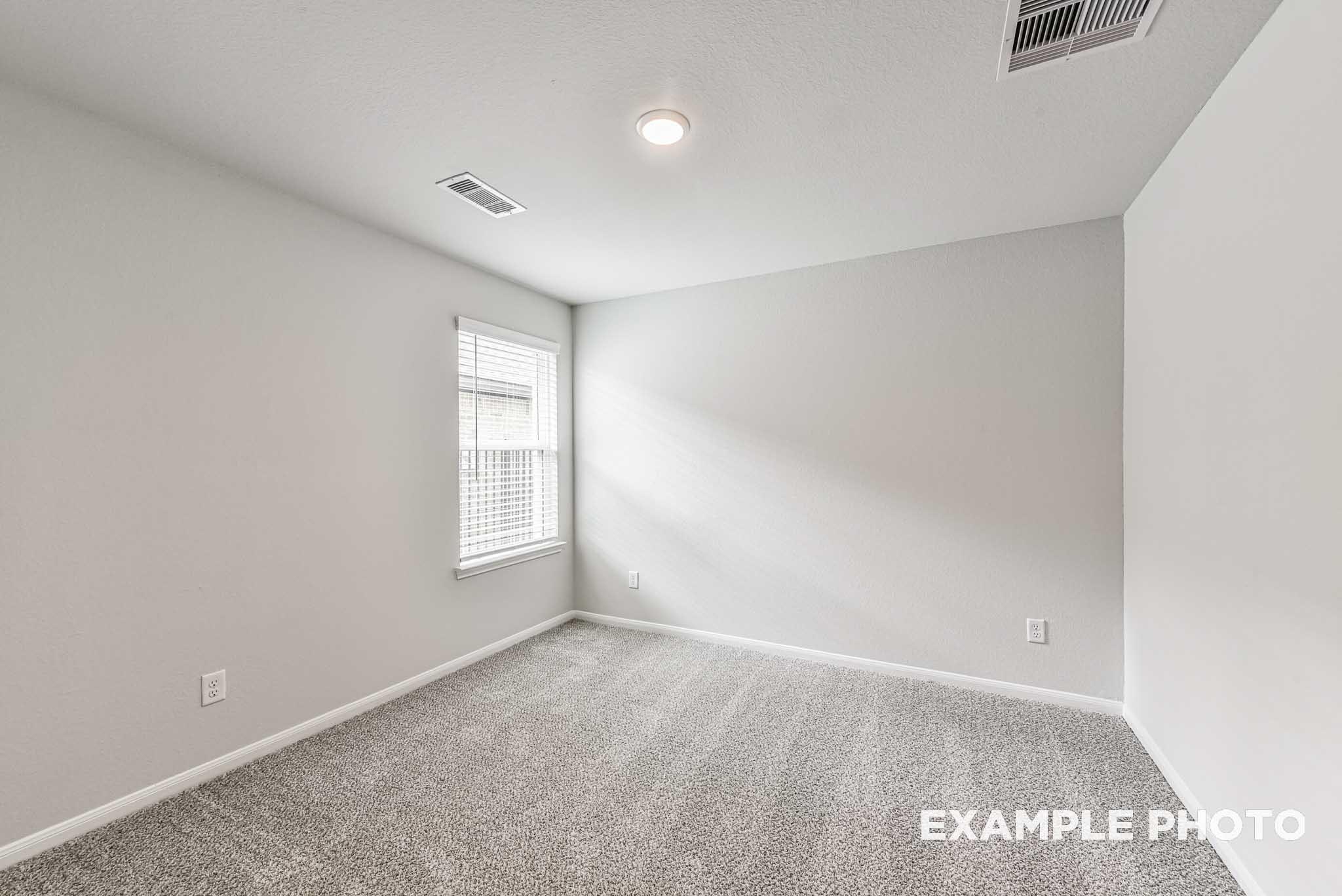 Empty secondary bedroom featuring gray walls, plush carpet, window blinds, and sloped ceiling in Davidson Homes The Riviera A, Rosharon, Texas