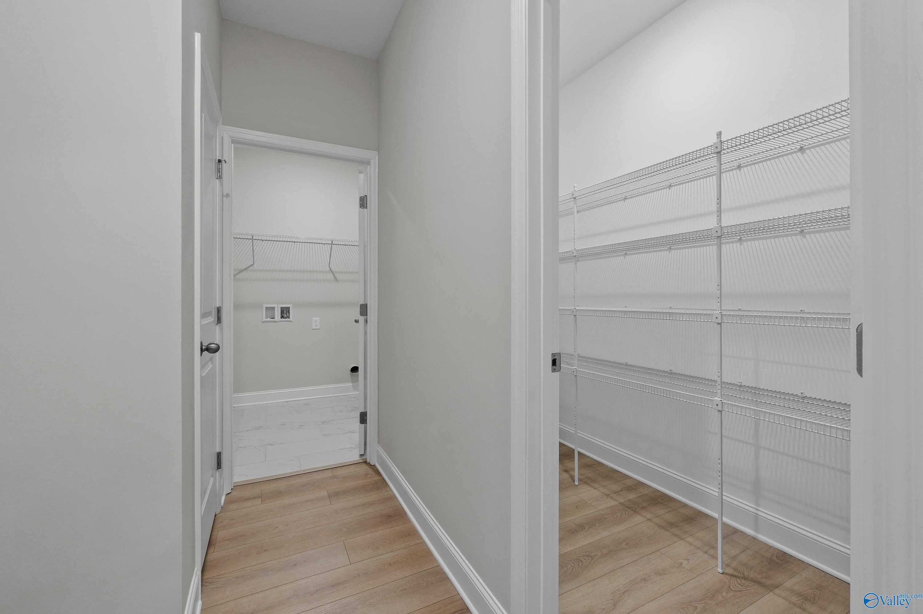 Modern laundry room with built-in shelving and washer/dryer space adjacent to wire-rack walk-in closet in Davidson Homes The Lanier, Harvest, AL