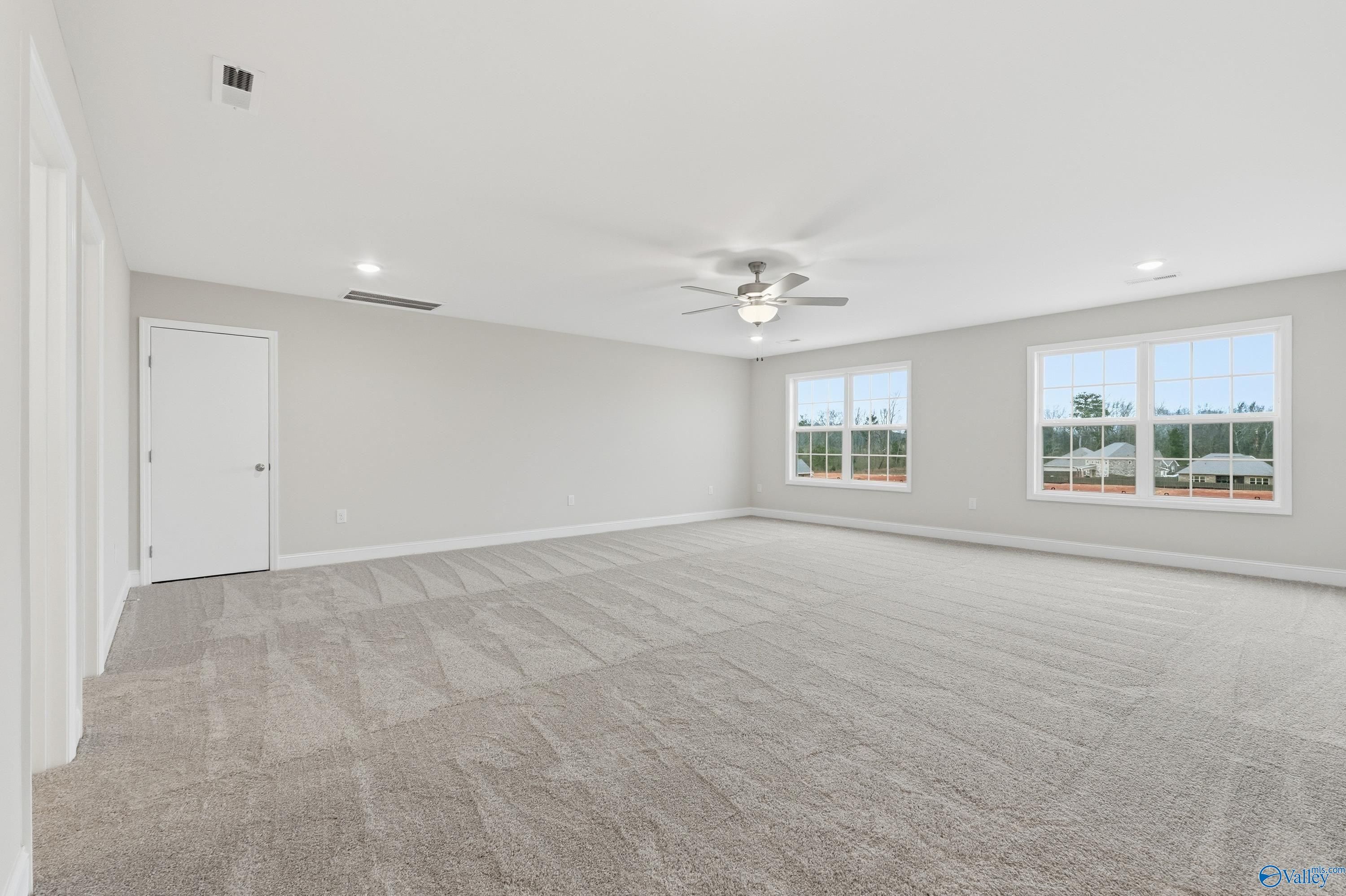 Spacious bedroom with gray carpet, ceiling fan, large windows overlooking woods in Davidson Homes The Kirkland, Decatur AL