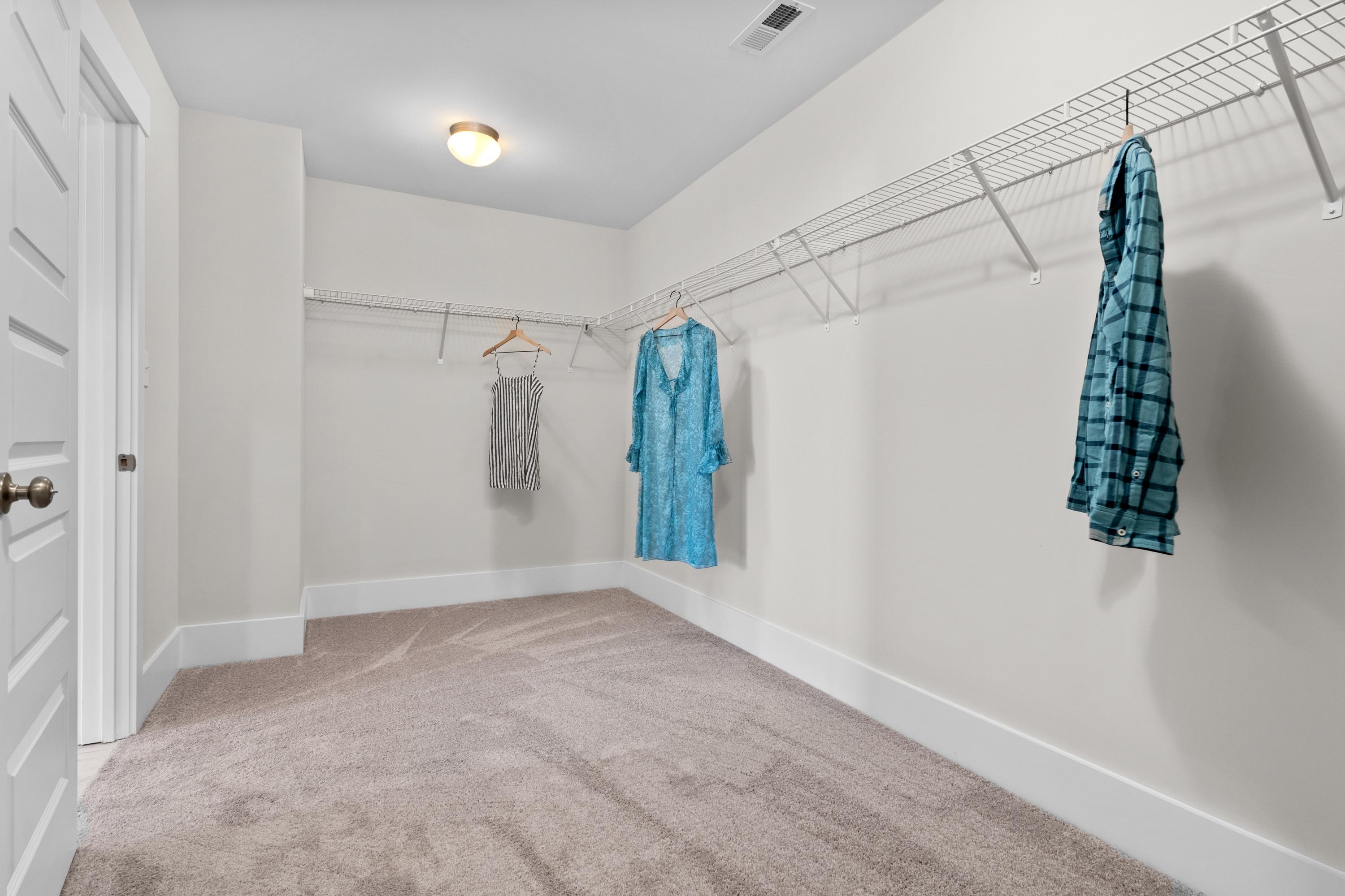 Spacious walk-in closet in The Chelsea A master suite, featuring wire shelving, hanging rods, and organized apparel on beige walls