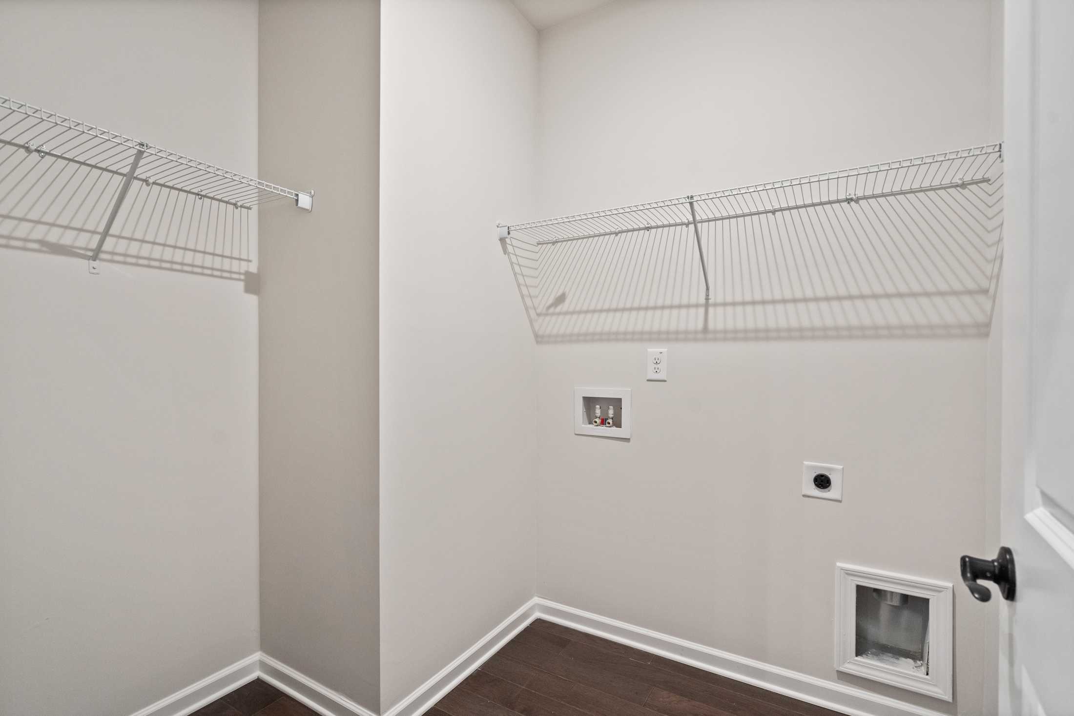 Spacious laundry room in The Glenwood B home with wire shelving, washer-dryer hookups, and pet door