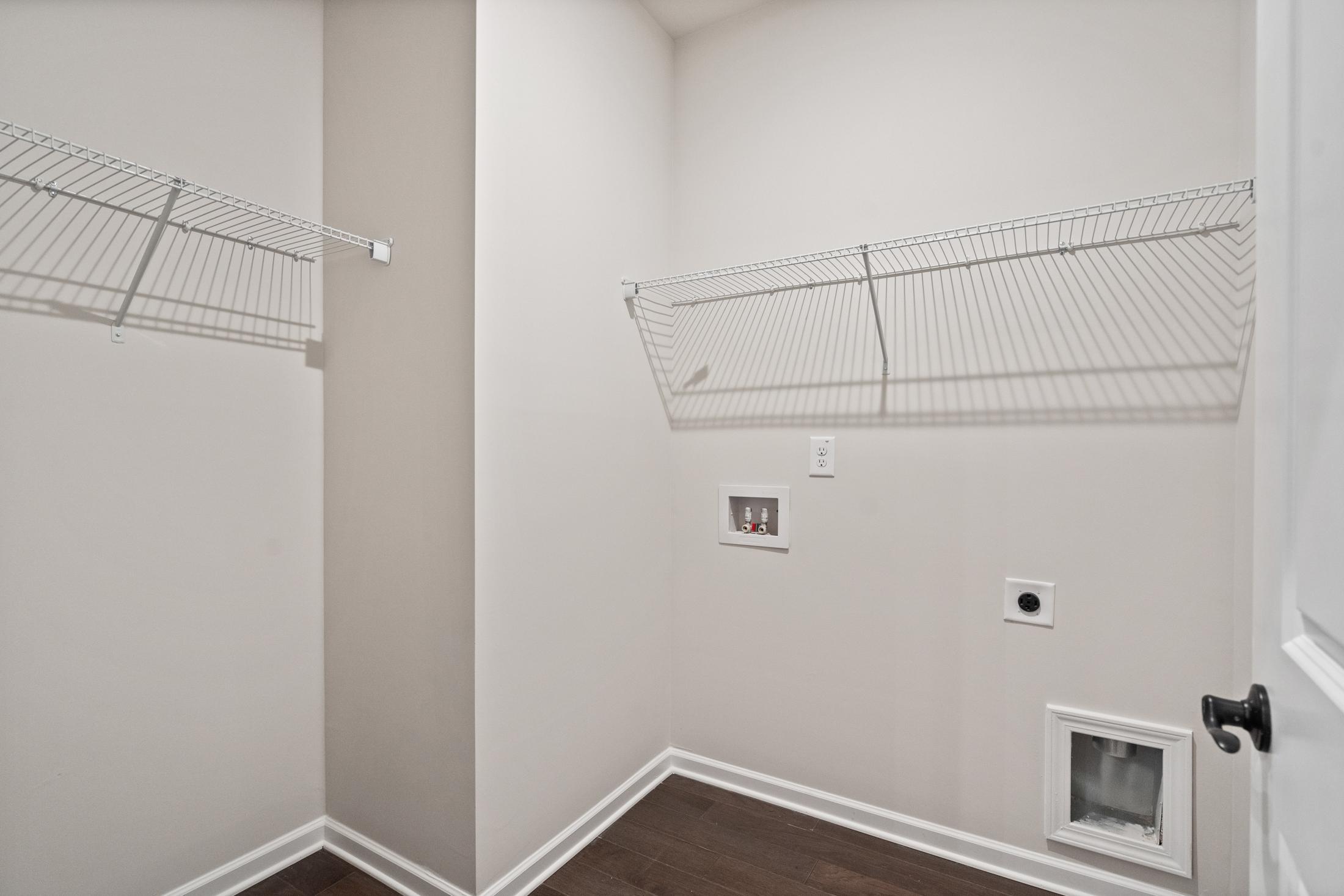 Spacious laundry room in The Glenwood with wire shelving, washer-dryer hookups, pet door, and beige walls