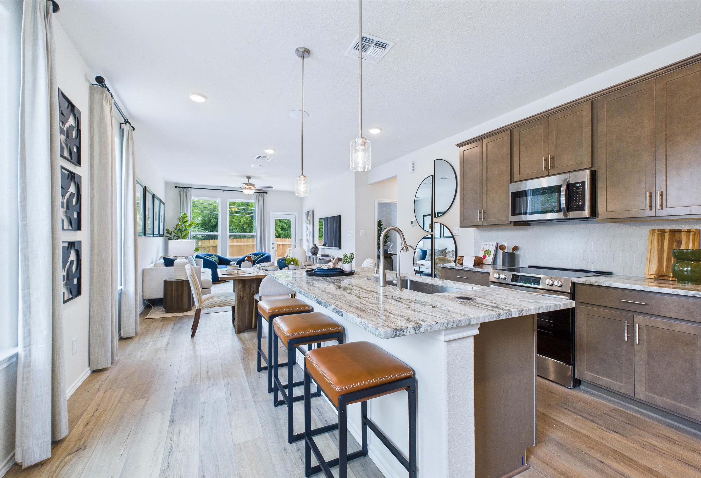 Open-concept kitchen in The Gillian C featuring a large stone island, modern cabinetry, and views of the dining area.