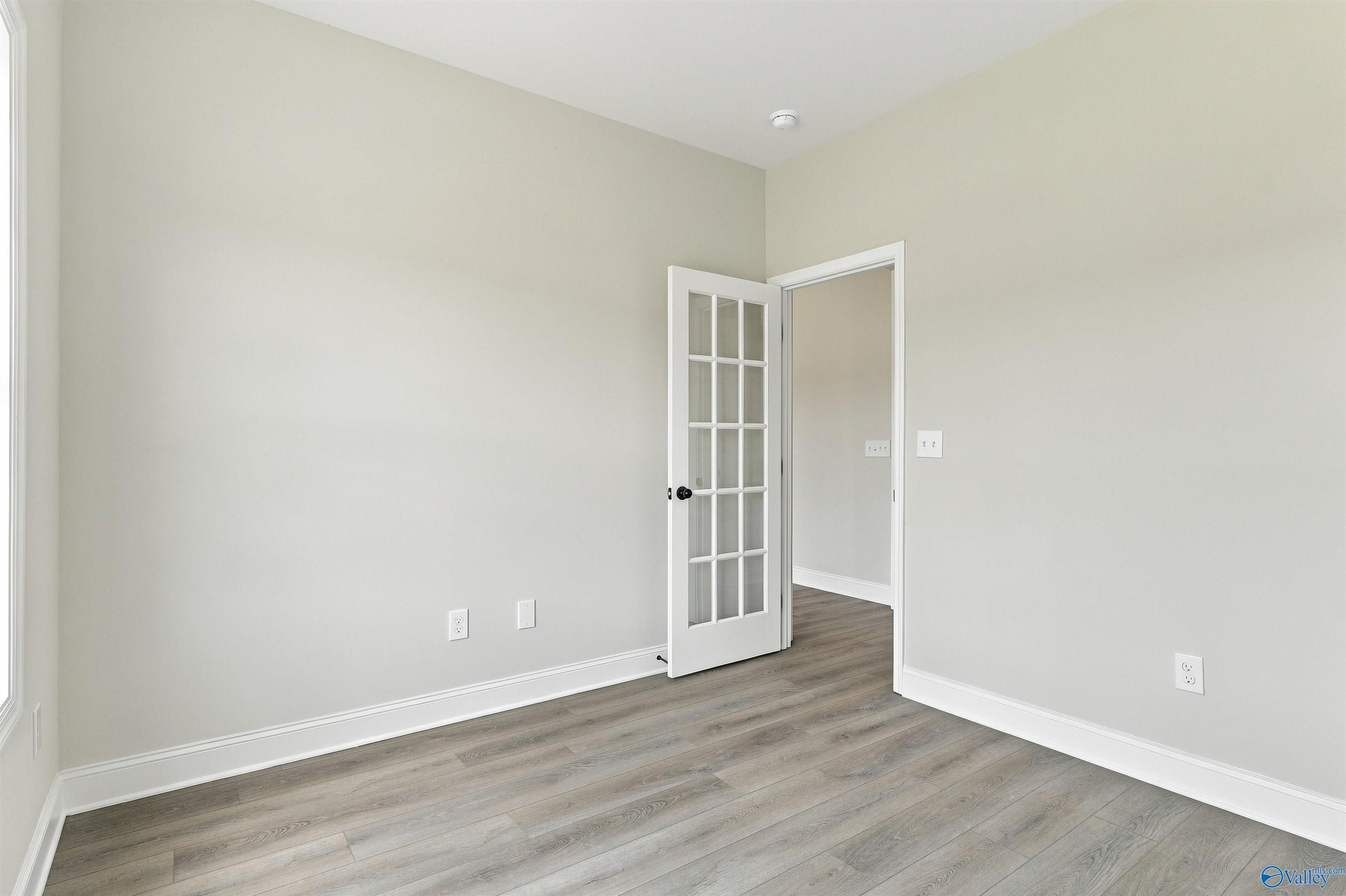 Empty flex room with glass-panel French door, gray wood-look flooring, and neutral walls in Davidson Homes The Shelby A, Athens, AL