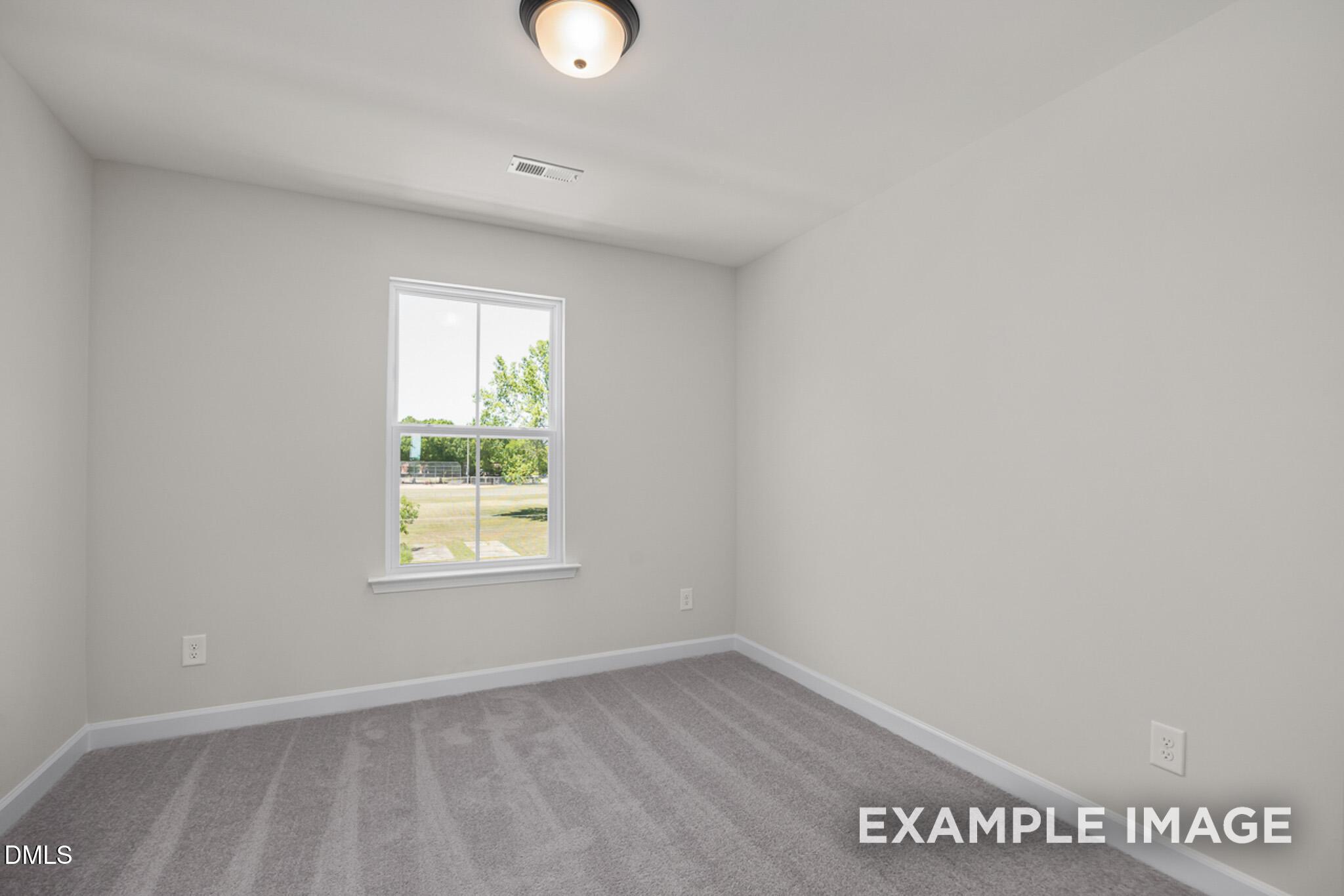 Bright, spacious secondary bedroom with neutral walls and plush carpet in The Mitchell floor plan at Camden Park, Knightdale.