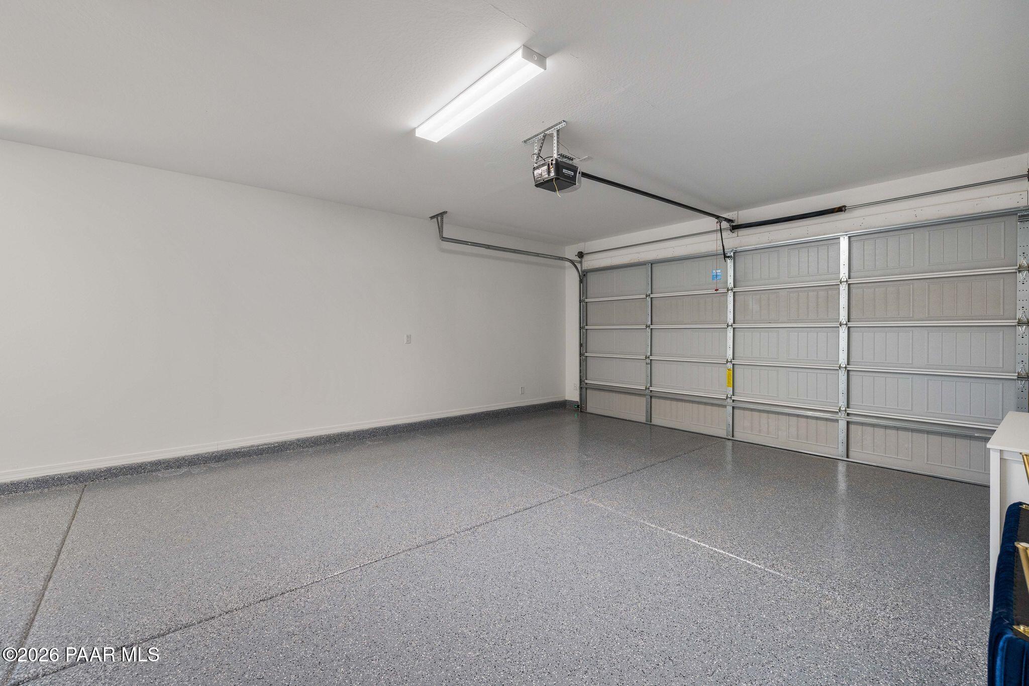 Spacious 3-car garage with epoxy flooring, white walls, and overhead lighting in Davidson Homes The Frontier A, Prescott Valley, AZ