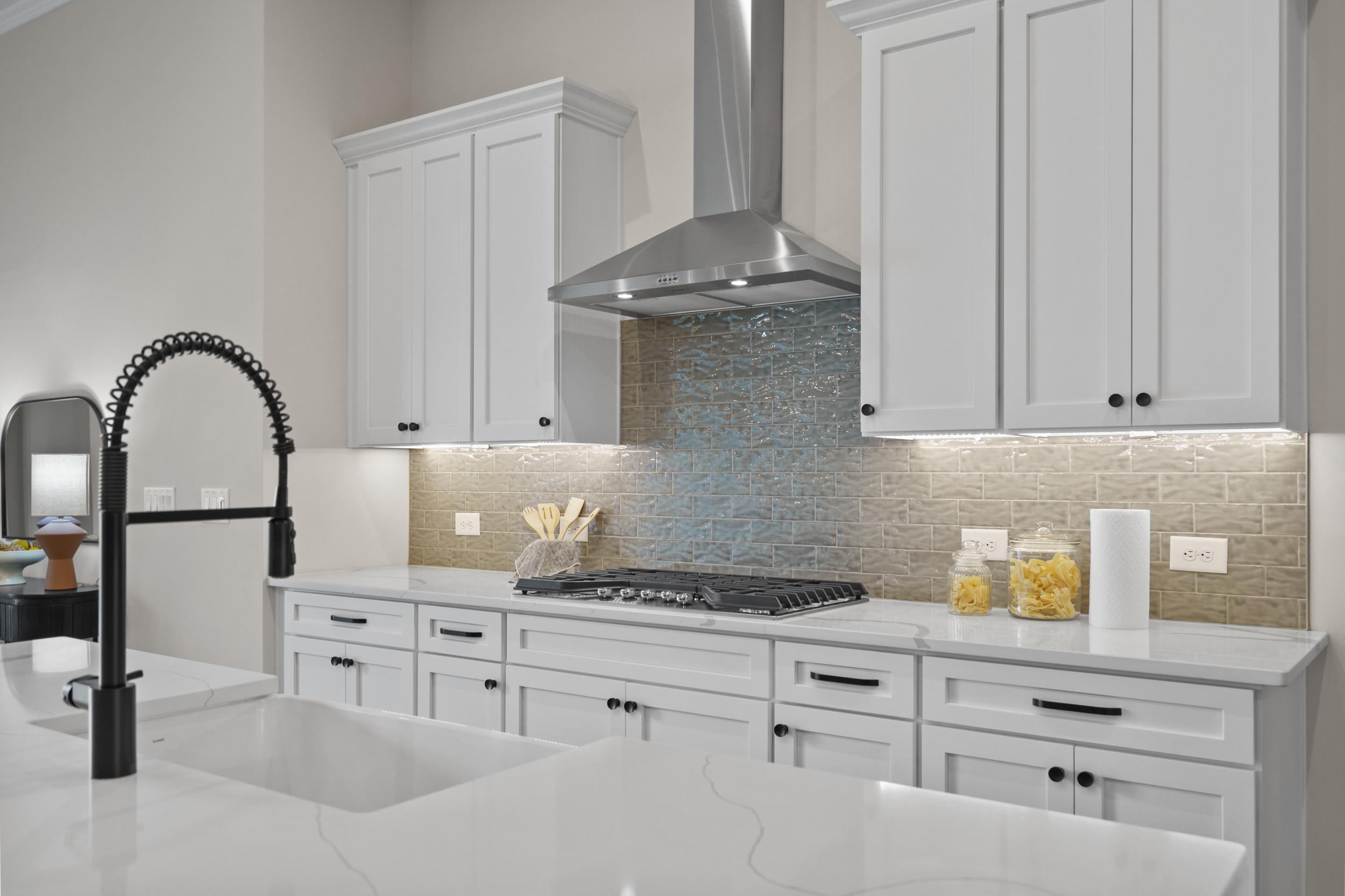 Spacious modern kitchen at The Village at Towne Lake in Woodstock GA with white shaker cabinets, blue mosaic backsplash, and quartz counters