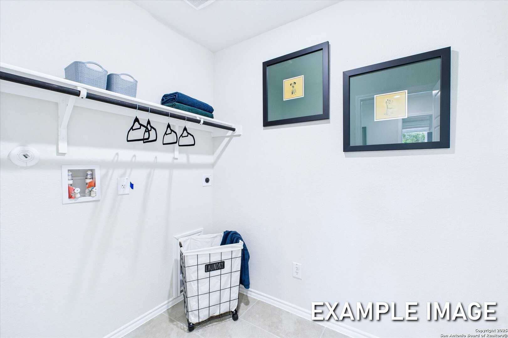 Organized laundry room with built-in shelves, hanging rods, blue bins, and wicker basket in Davidson Homes The Gillian B, San Antonio
