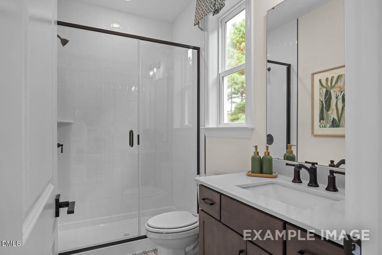 Modern master bathroom with frameless glass shower, white subway tiles, and dark wood vanity in Davidson Homes The Crawford D, Angier, NC
