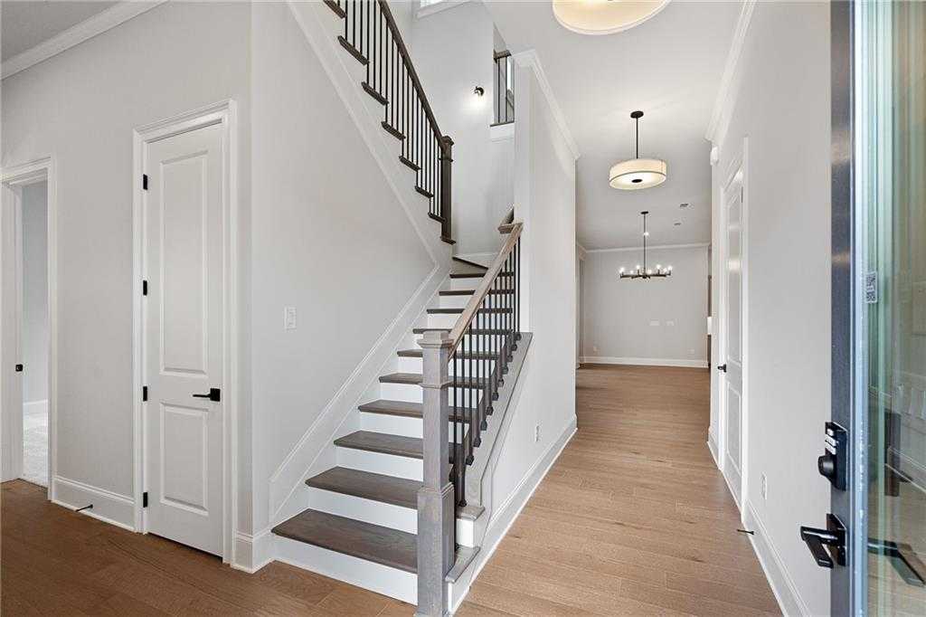 Grand two-story staircase with wrought-iron railing and chandelier in airy foyer of Davidson Homes Seaside B, Woodstock GA