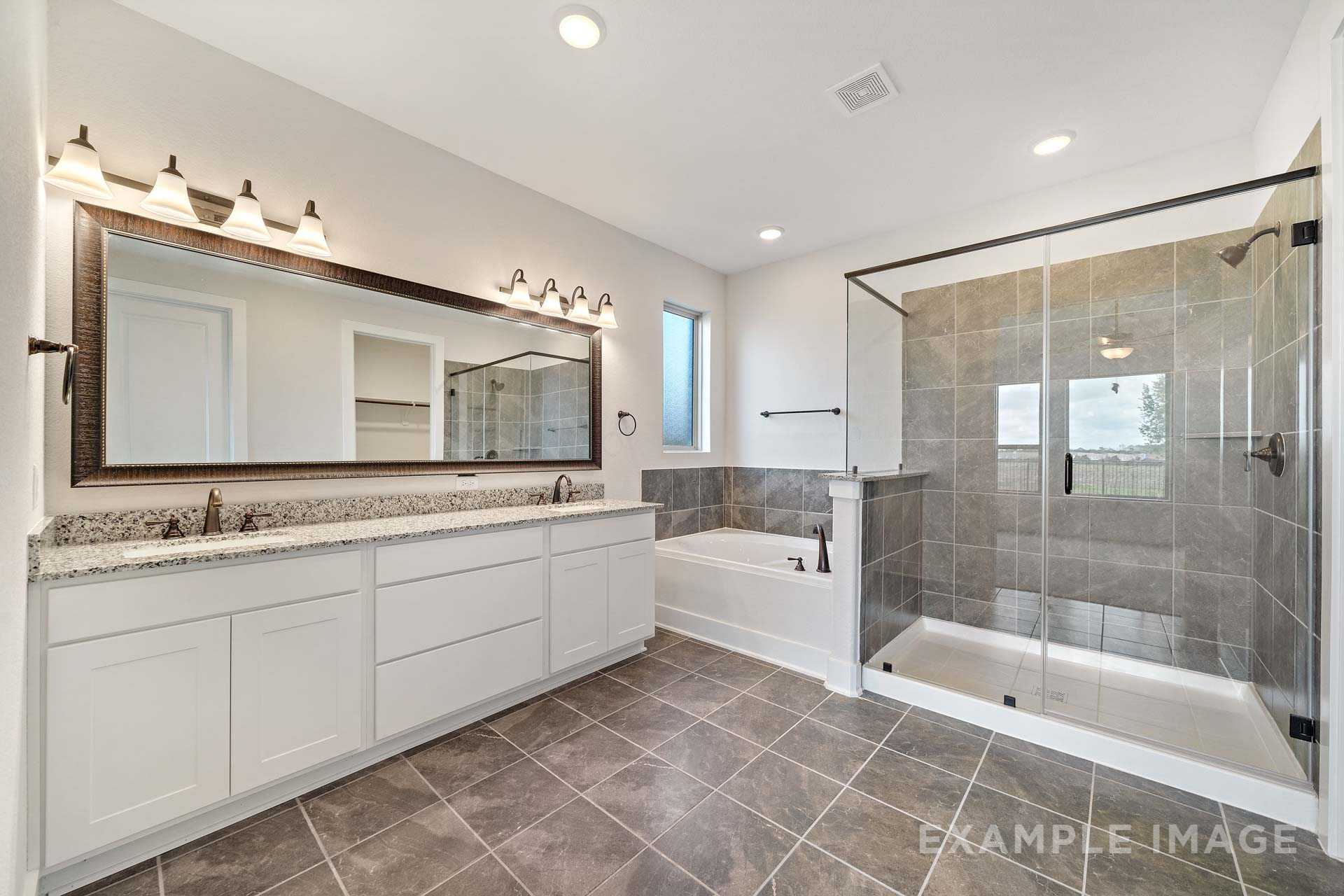 Luxurious master bathroom in The Victoria A with double vanity, soaking tub, and frameless glass shower