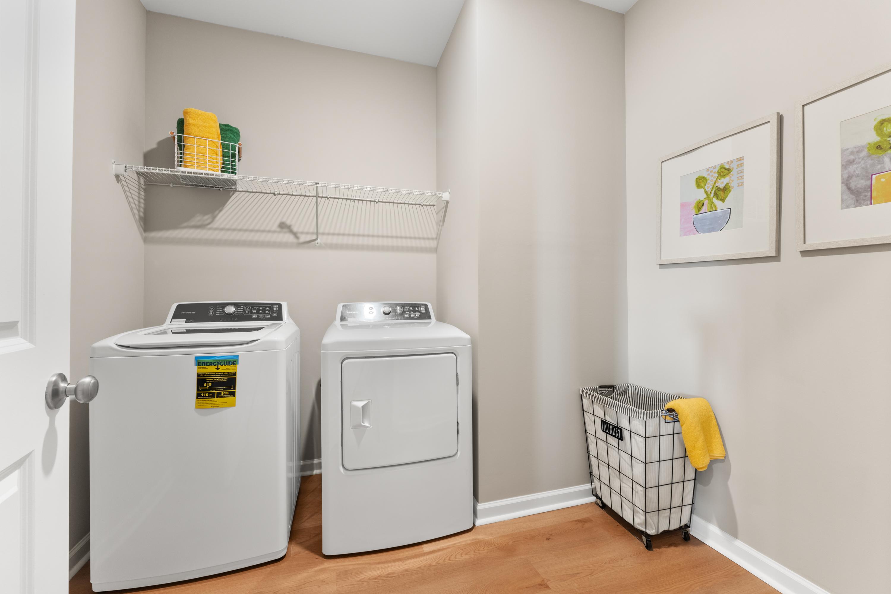 Spacious laundry room at The Meadows at Hampton Cove in Owens Cross Roads AL with white washer dryer, yellow towels, and hardwood floors