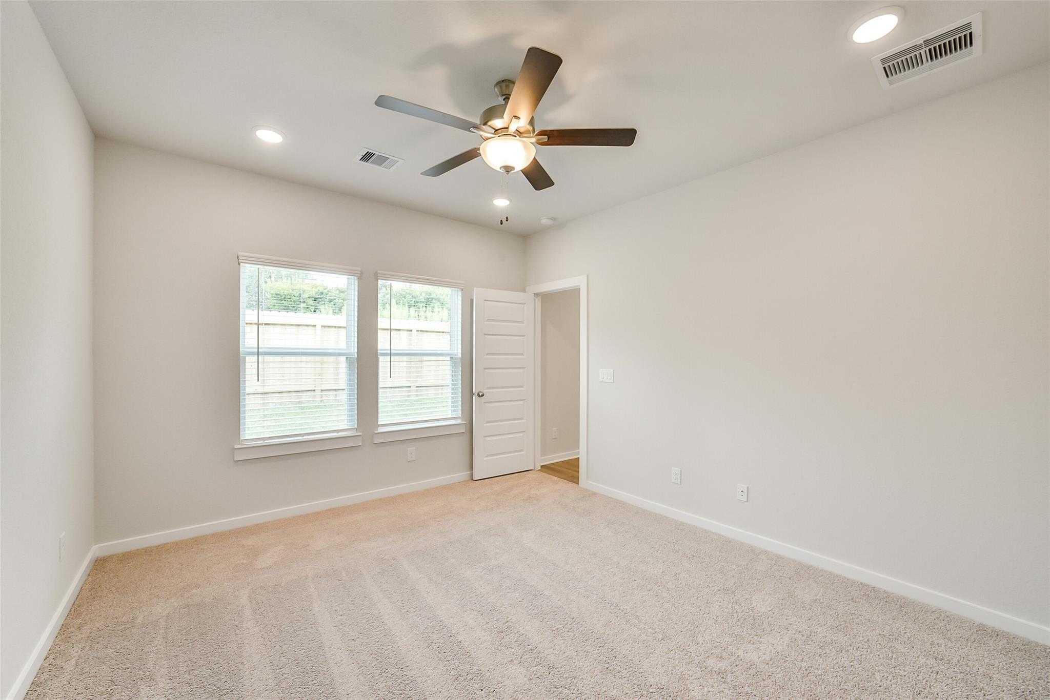 Bright secondary bedroom with neutral walls, beige carpet, double windows, ceiling fan in Davidson Homes The Blanco E, Magnolia TX