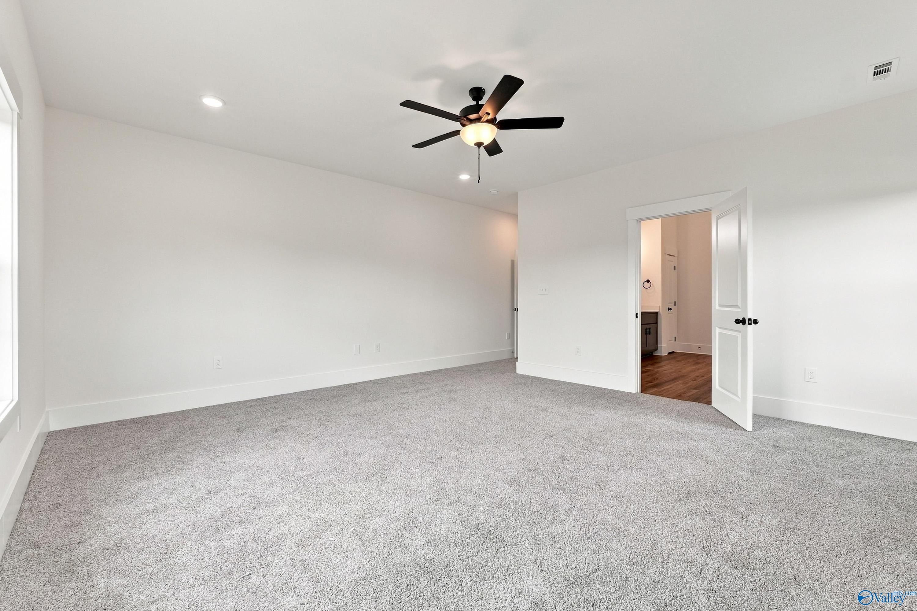 Spacious primary bedroom with gray carpet and black ceiling fan in Davidson Homes The Valencia, Riverton Preserve, Huntsville